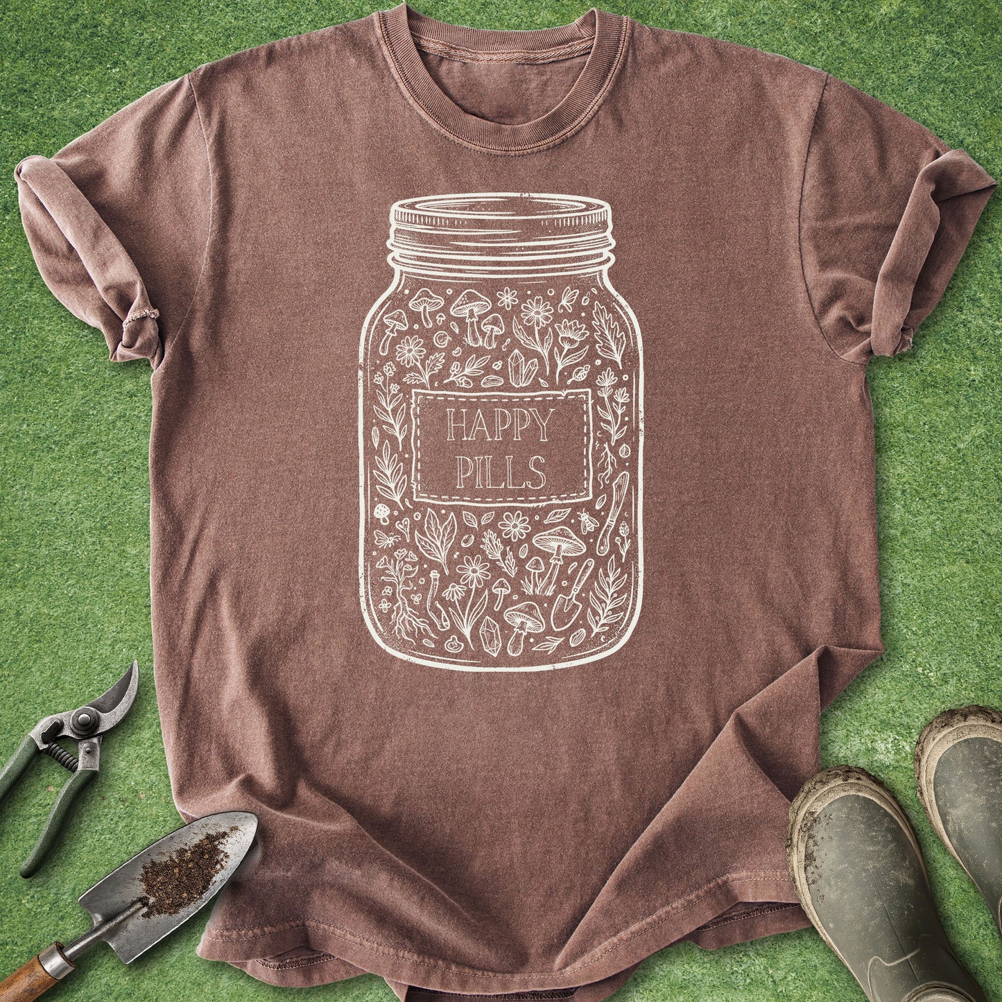 Brown t-shirt with a 'Happy Pills' jar design on a green grass background