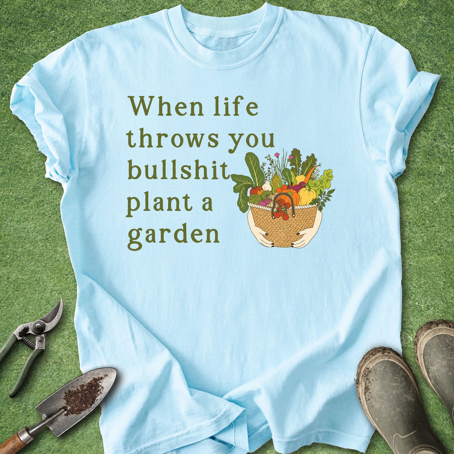 Light blue t-shirt with gardening graphic and text on a green background