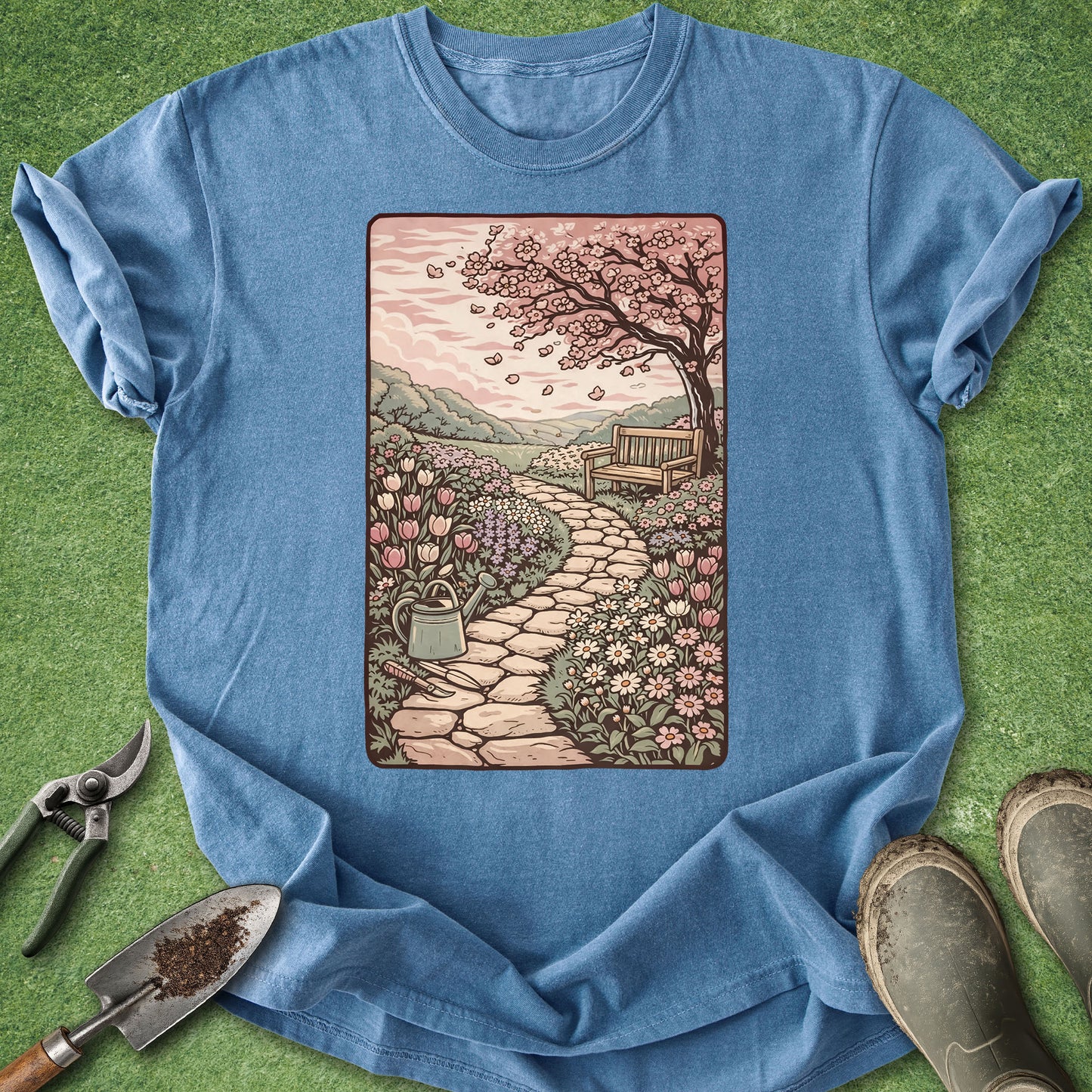 Blue t-shirt with a garden scene graphic on a green grass background