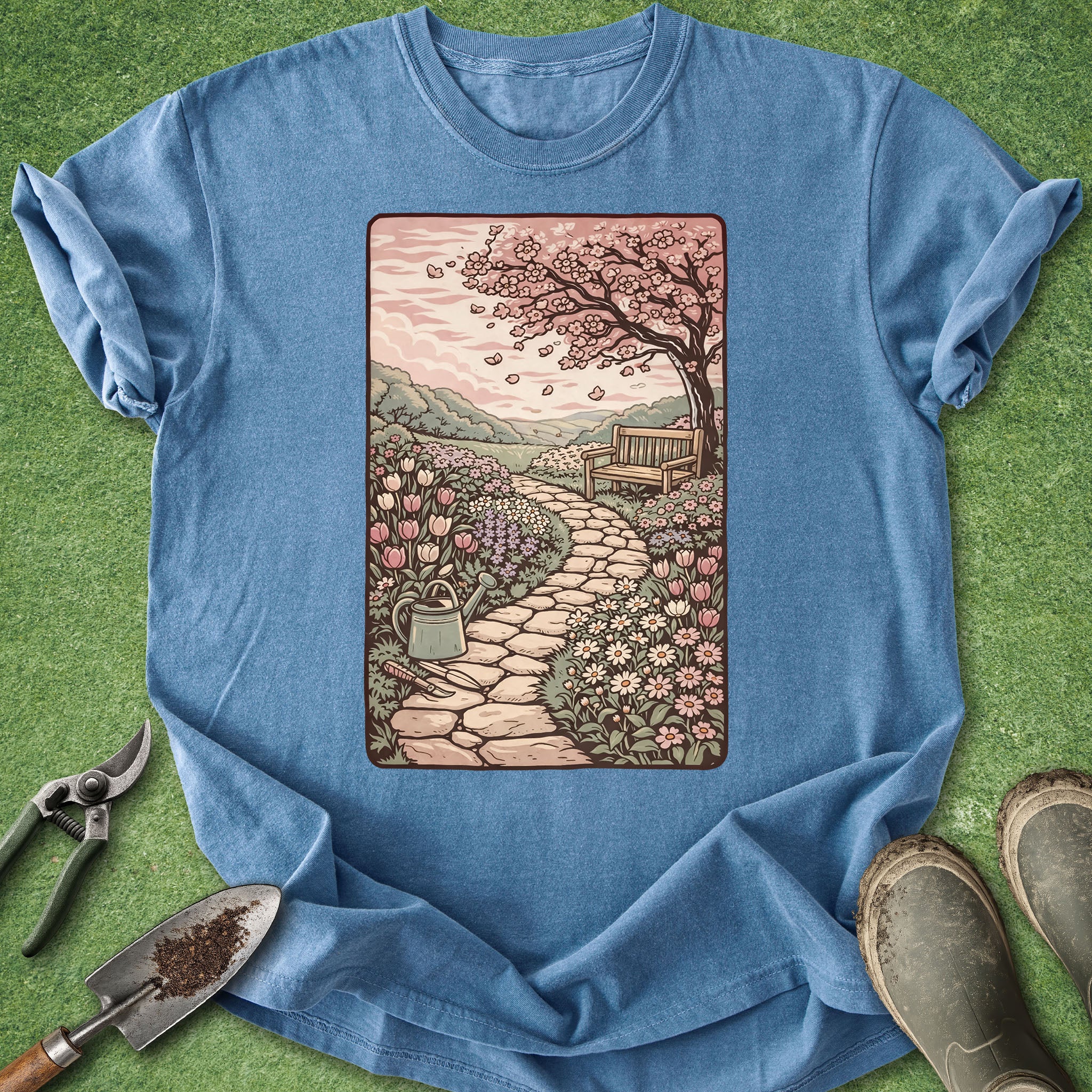 Blue t-shirt with a garden scene graphic on a green grass background