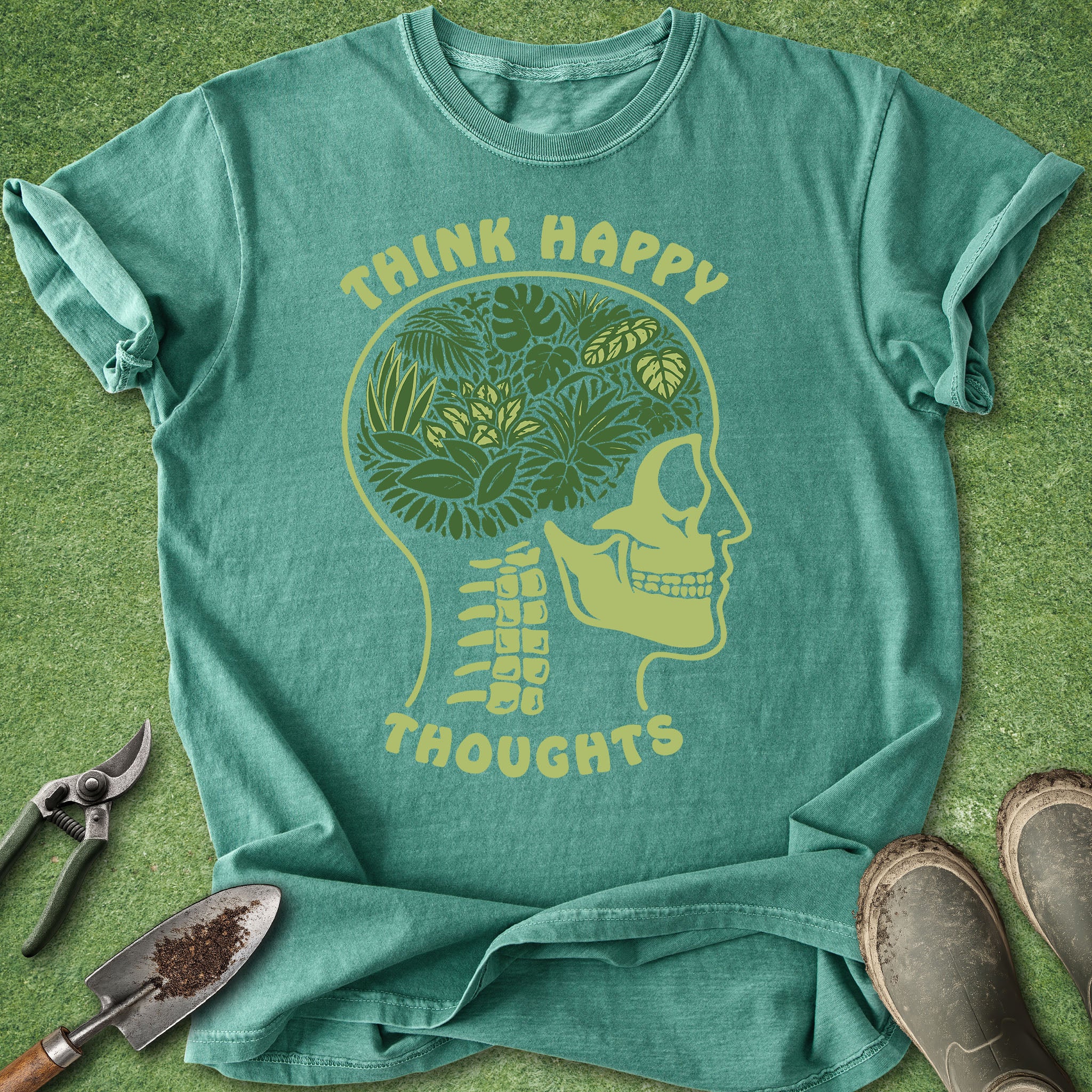 Teal t-shirt with skull and foliage design on a green background