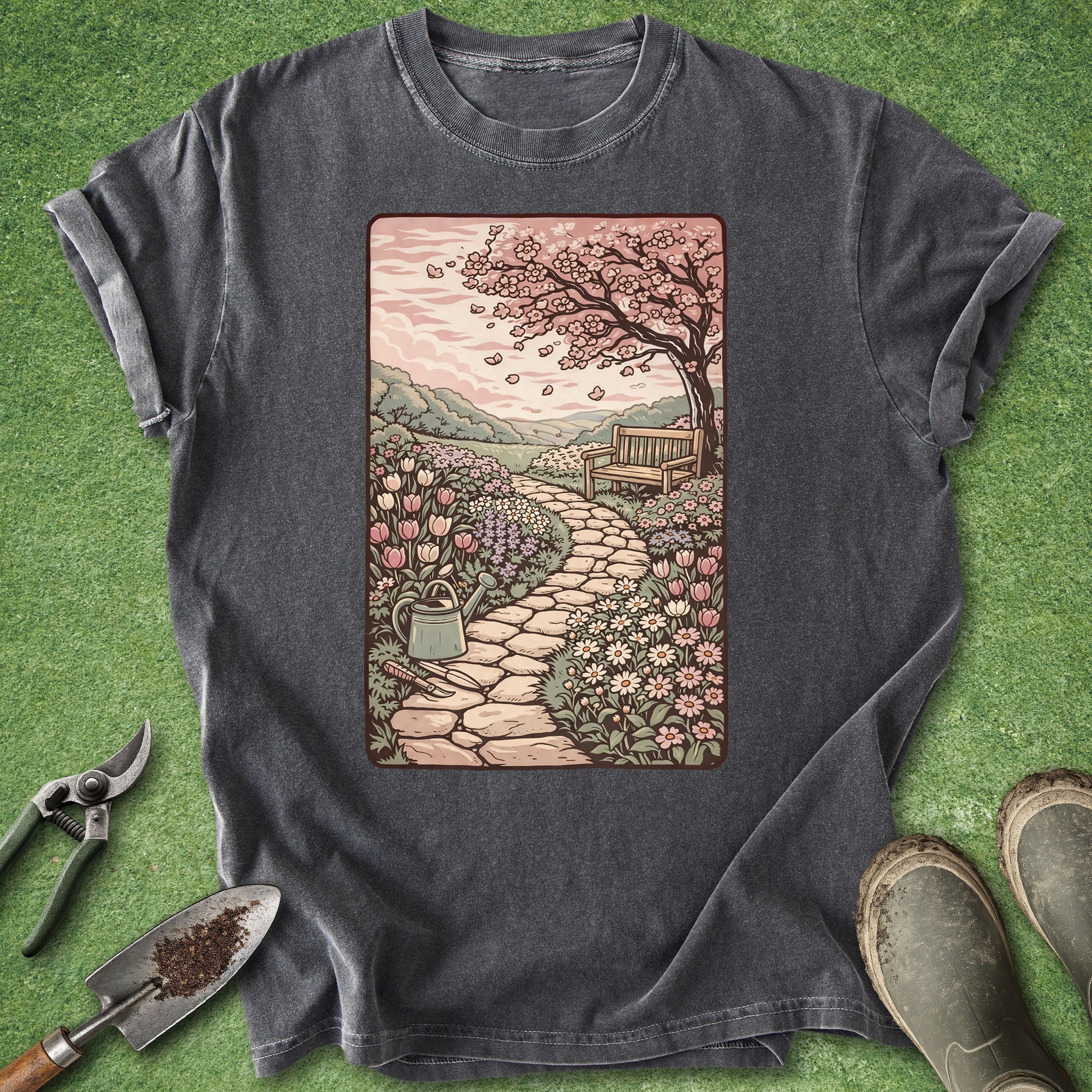 Gray t-shirt with a garden scene graphic on a green grass background