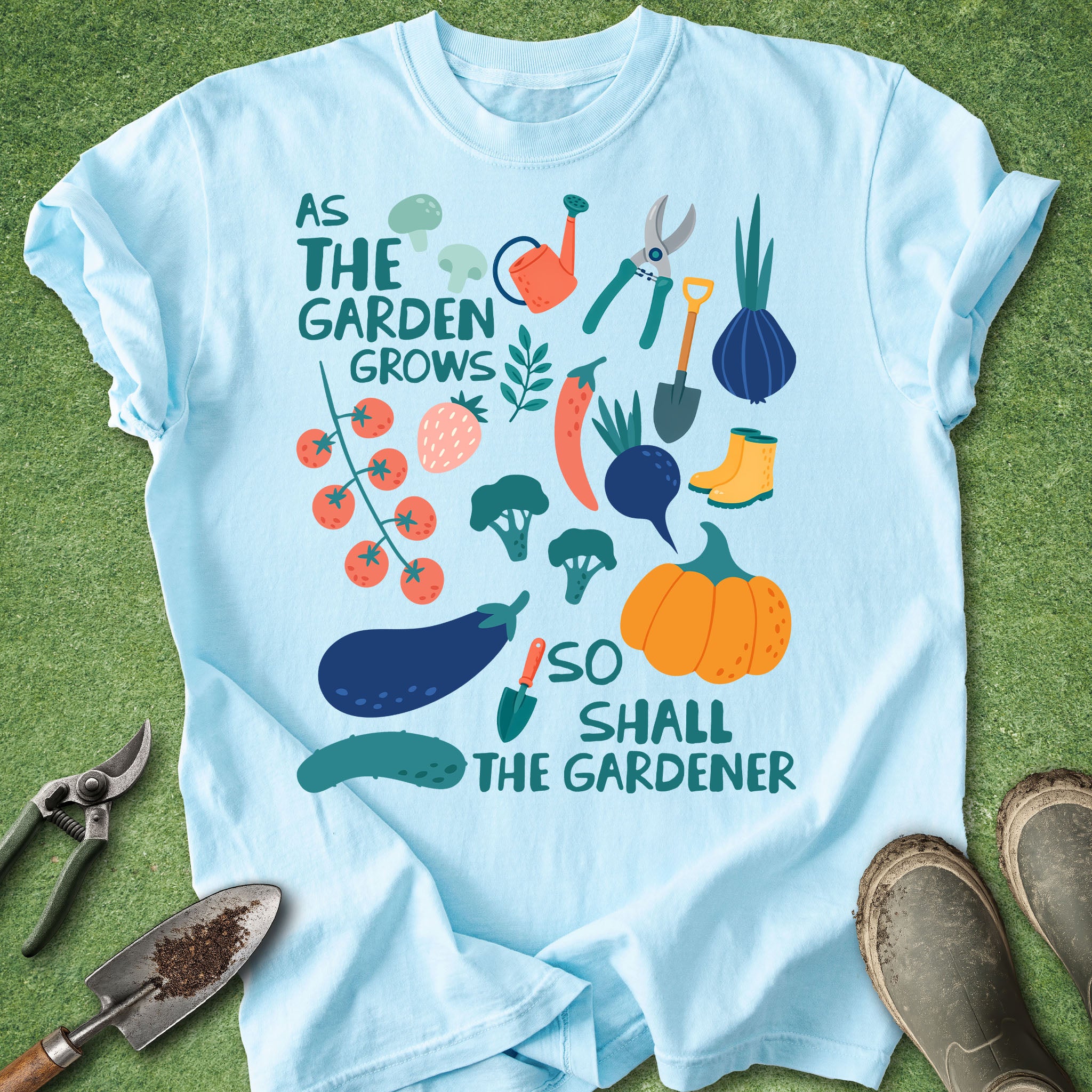 Light blue t-shirt with “As the garden grows so shall the gardener” text and colorful illustrations of vegetables and gardening tools