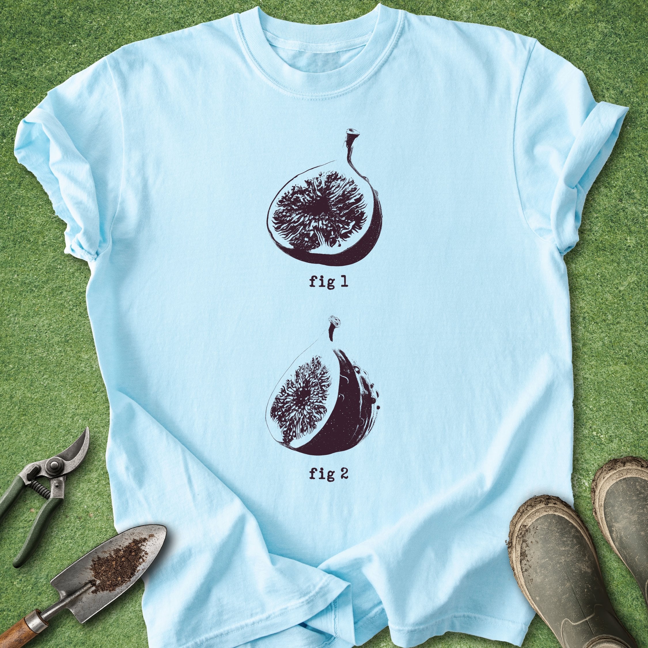 Light blue t-shirt with fig illustrations on a green grass background