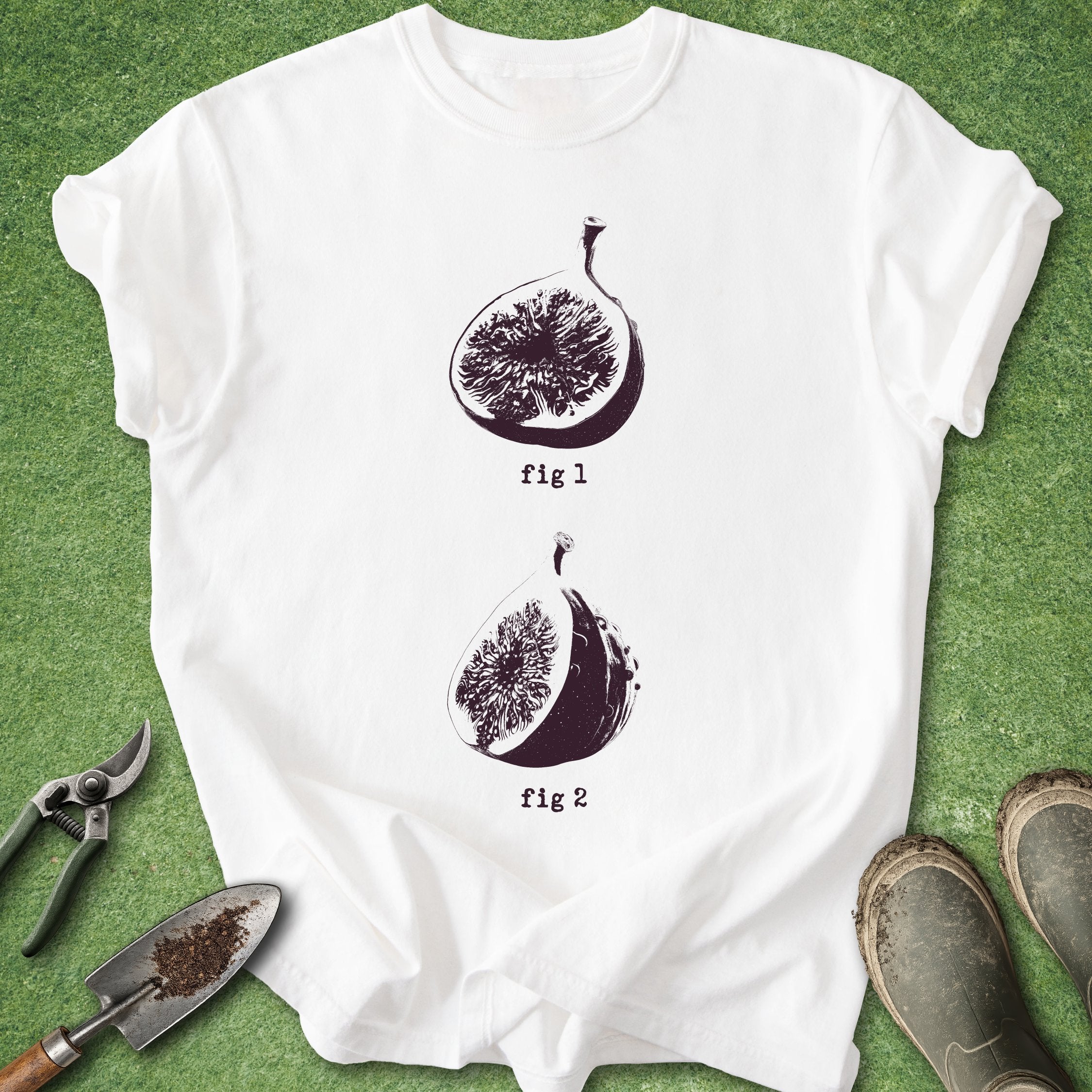 White t-shirt with fig illustrations on a green surface with gardening tools.