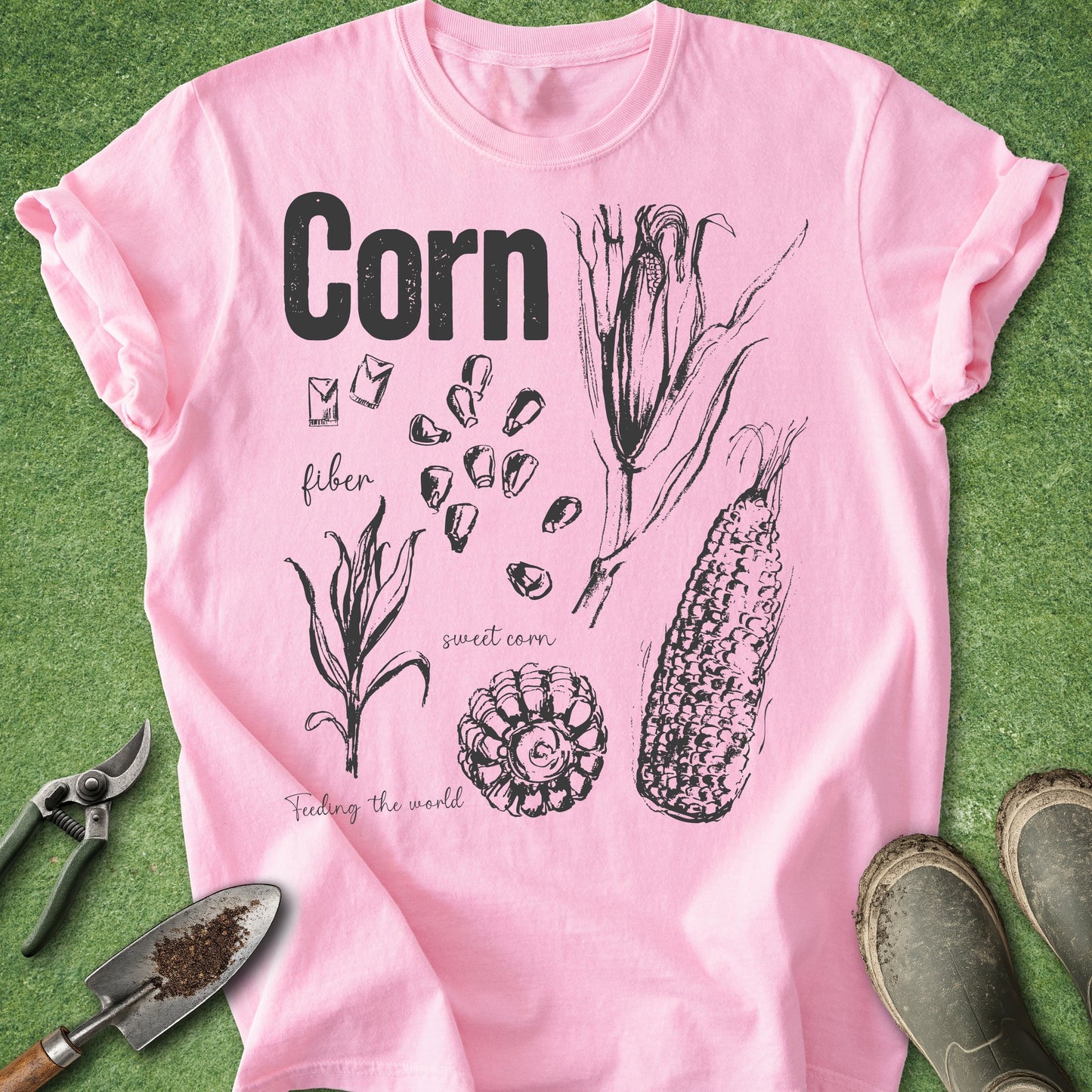 Pink t-shirt with corn illustration and text on a green background