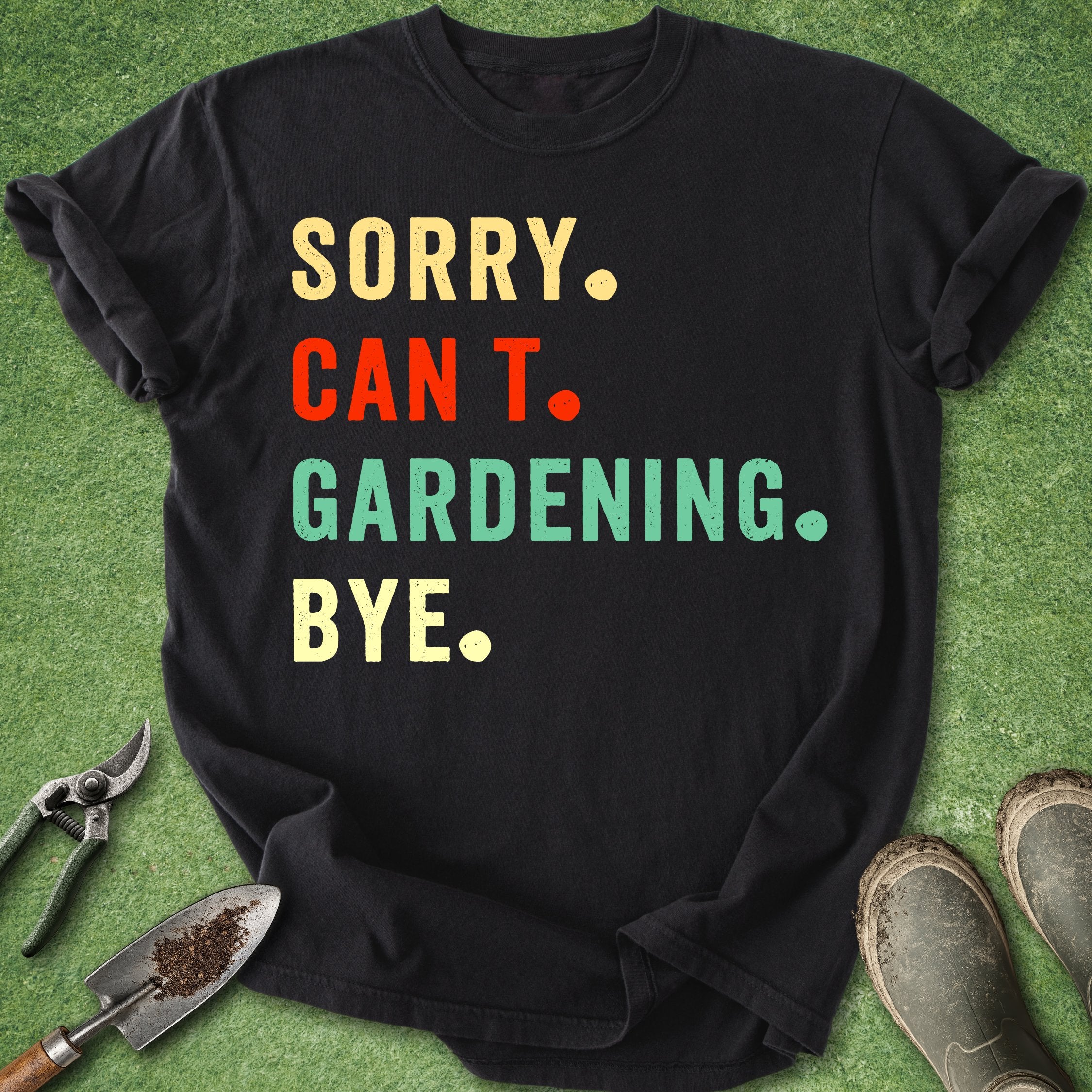Black t-shirt with colorful text 'SORRY. CAN'T. GARDENING. BYE.' on a grass background with gardening tools.