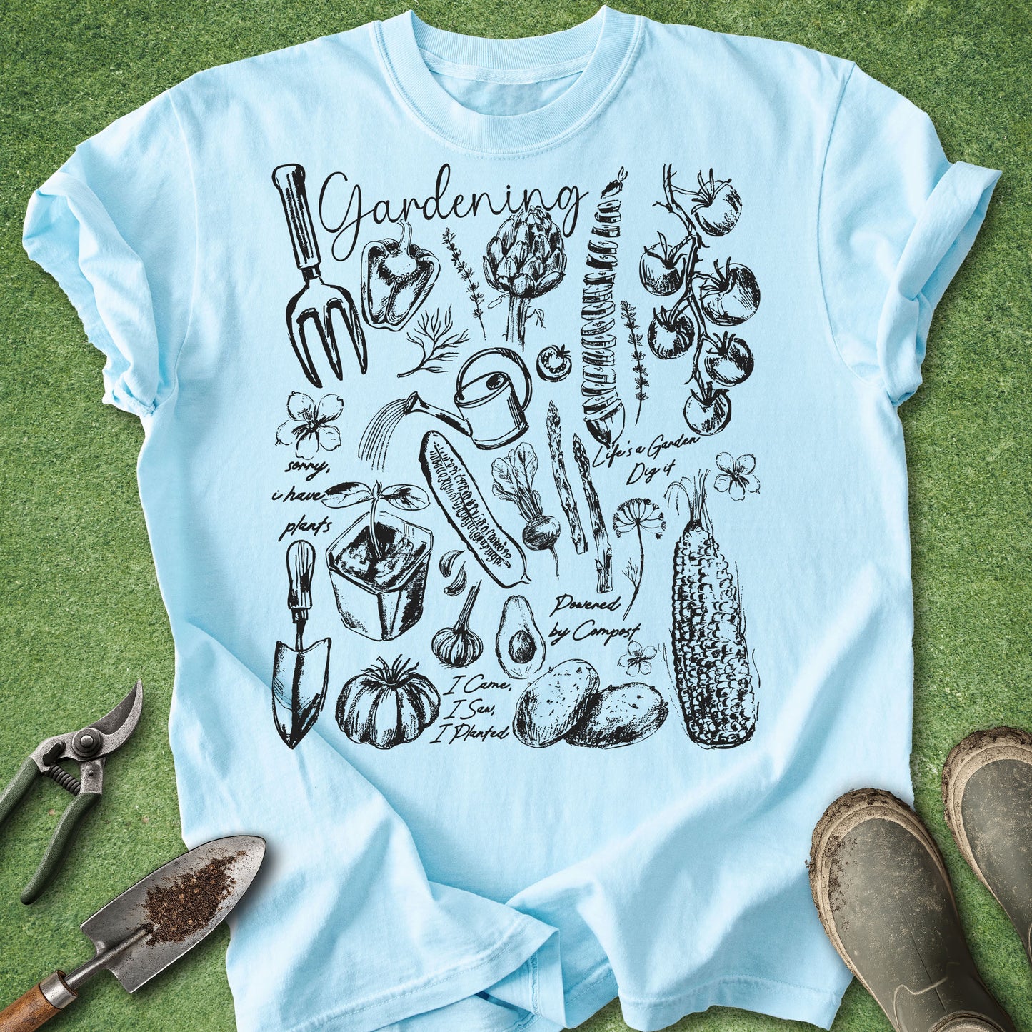 Light blue t-shirt with black gardening illustrations on a green grass background