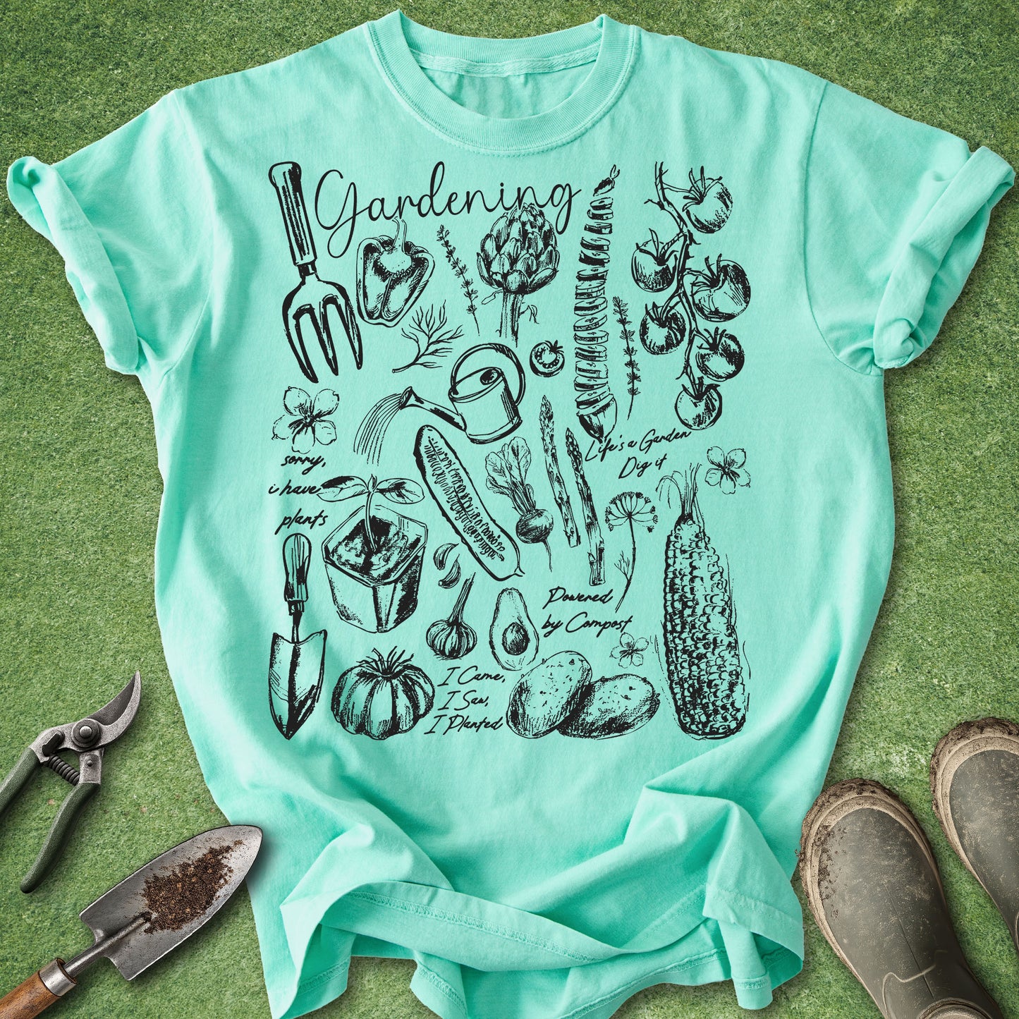 Mint green t-shirt with gardening illustrations on a grass background