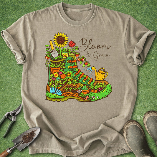 Beige t-shirt with a colorful gardening boot graphic and 'Bloom & Grow' text on a green grass background.