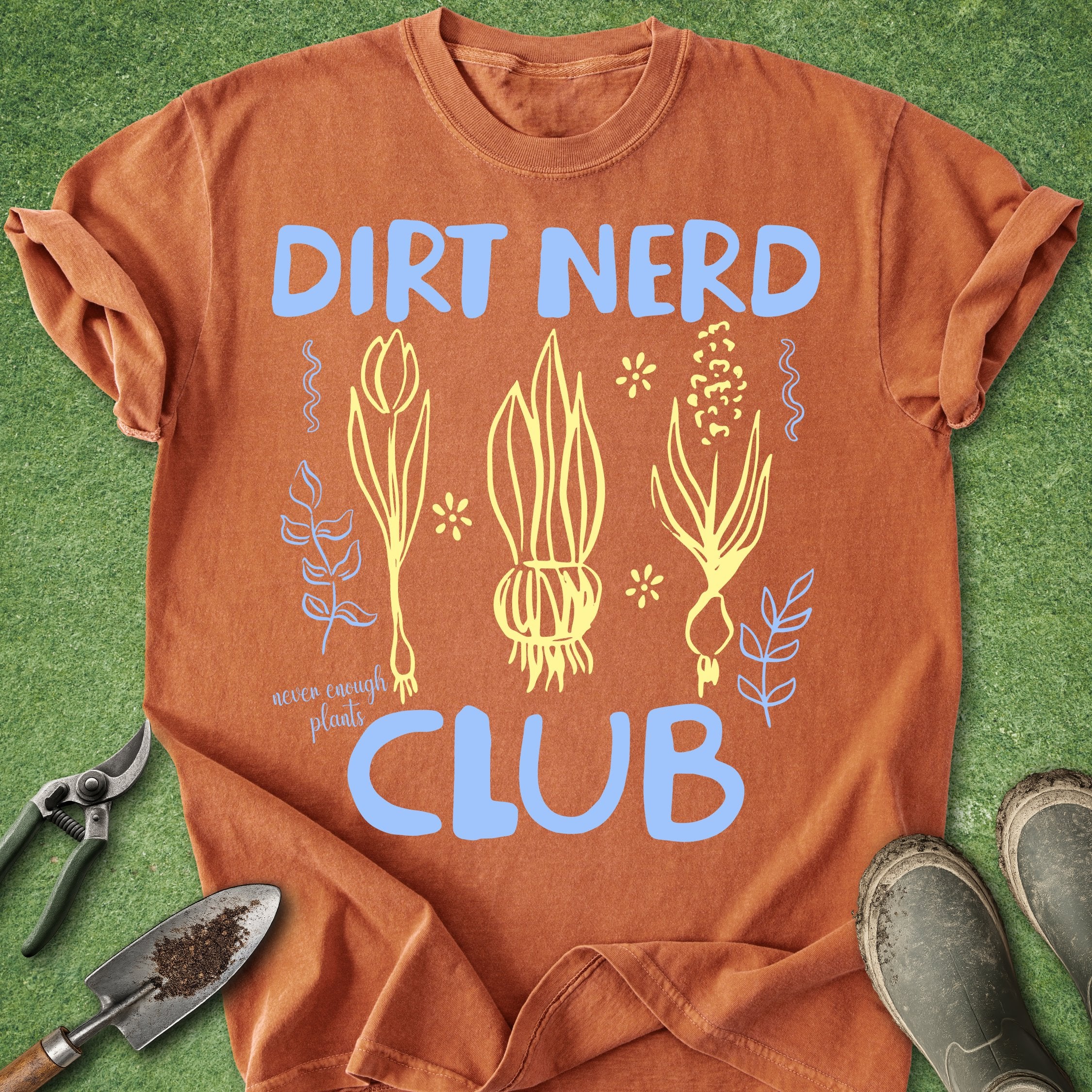 Orange t-shirt with 'Dirt Nerd Club' text and gardening tools on a grass background