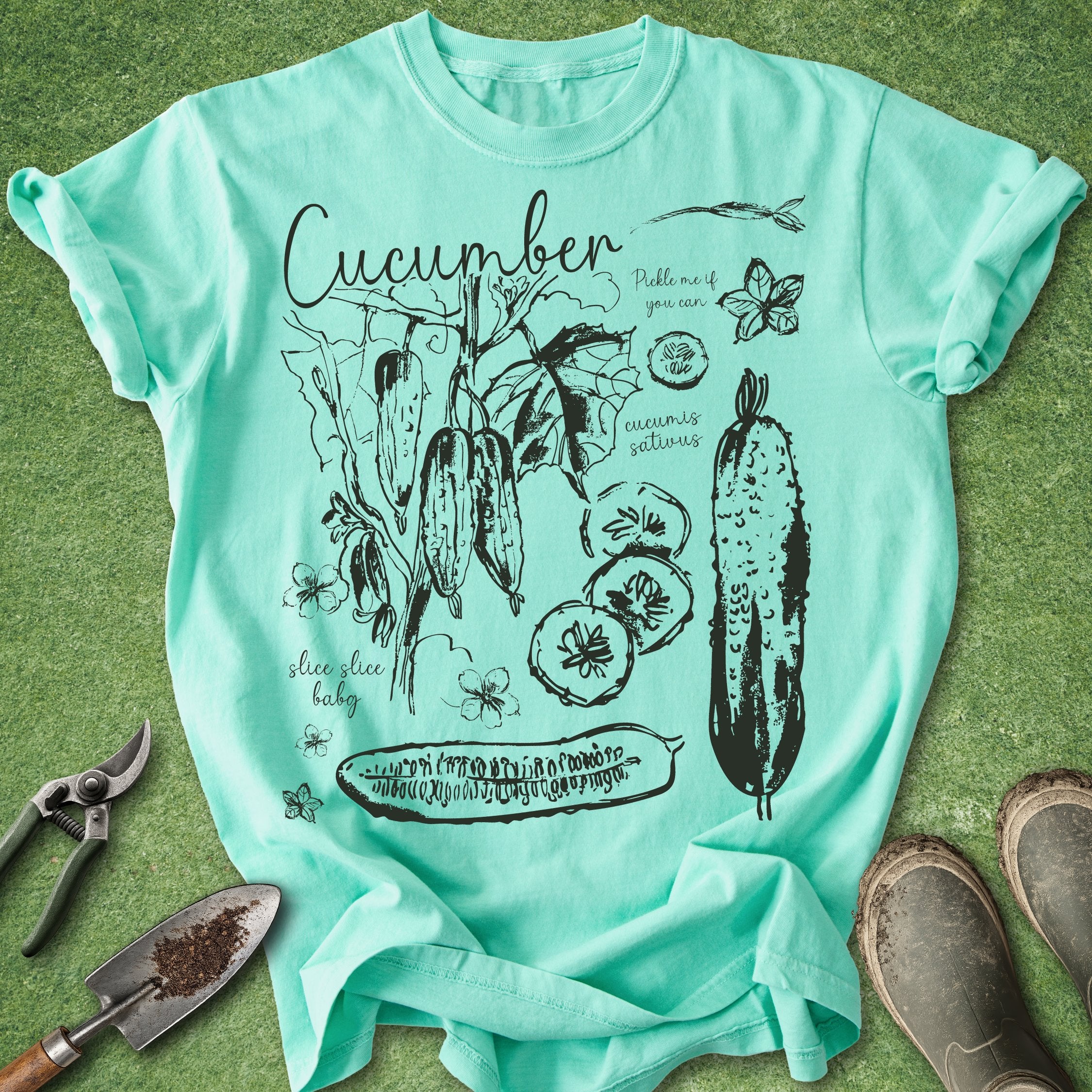 Mint green t-shirt with cucumber graphic design on a grass background