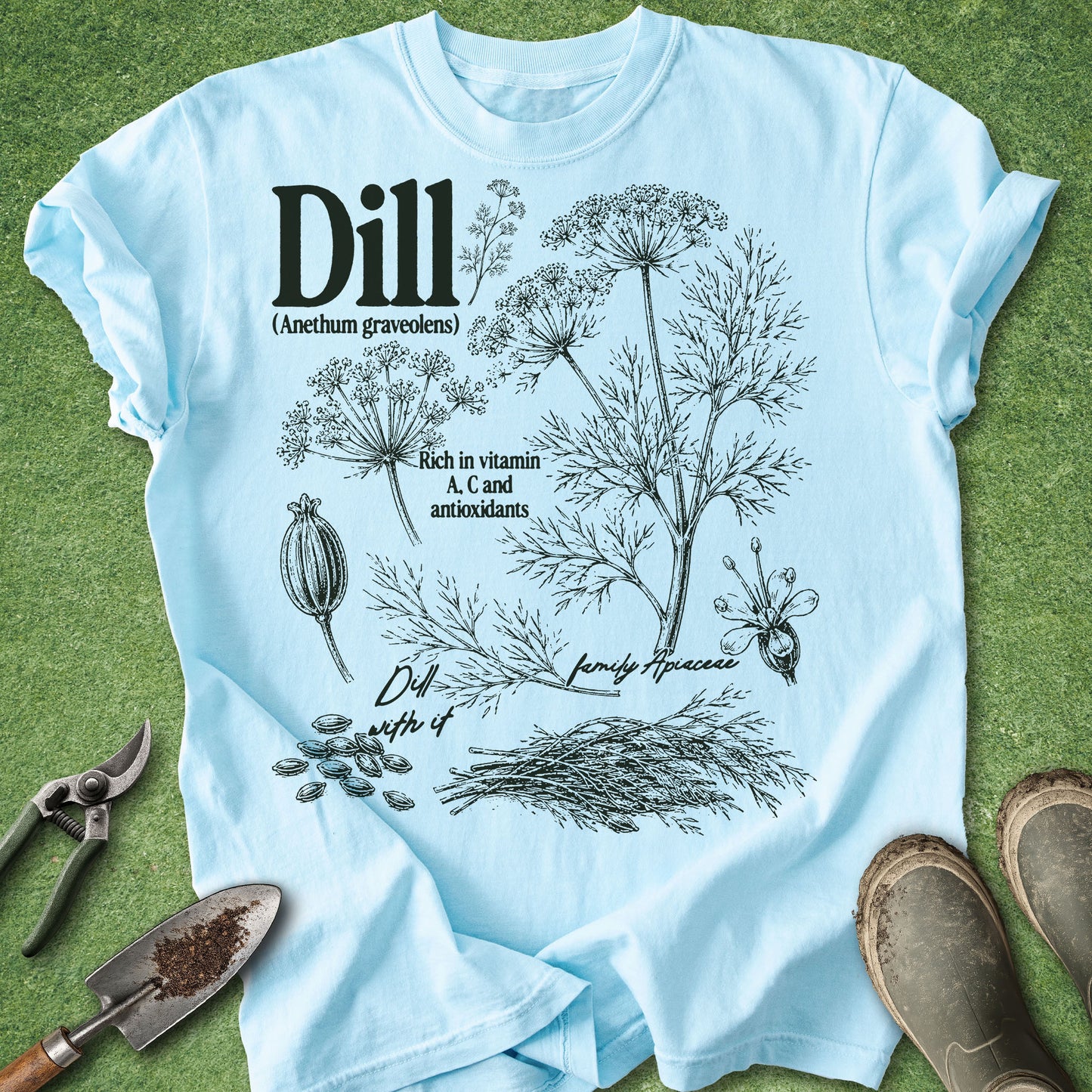 Light blue t-shirt with dill plant illustration on a grass background