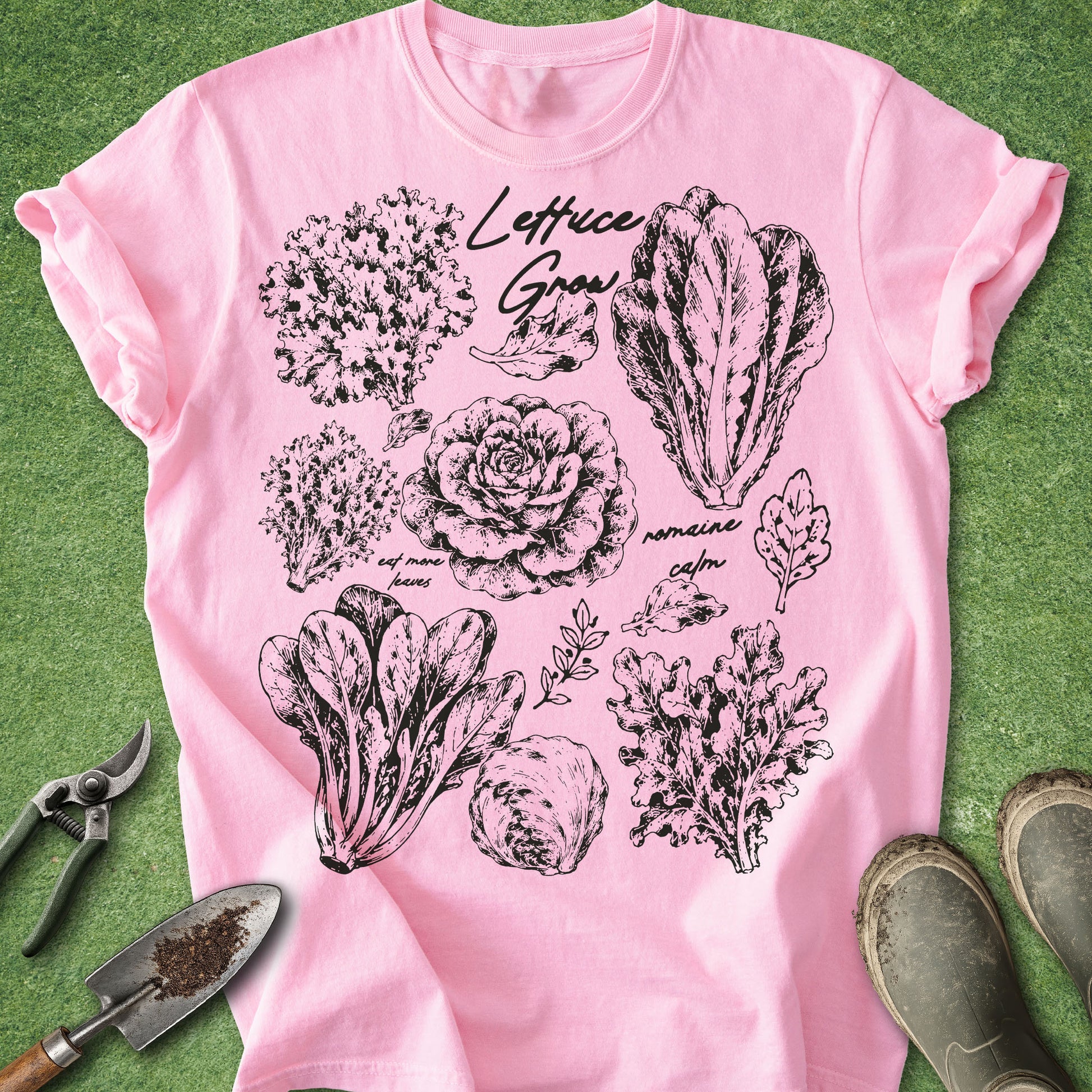Pink t-shirt with black vegetable illustrations and text on a green background