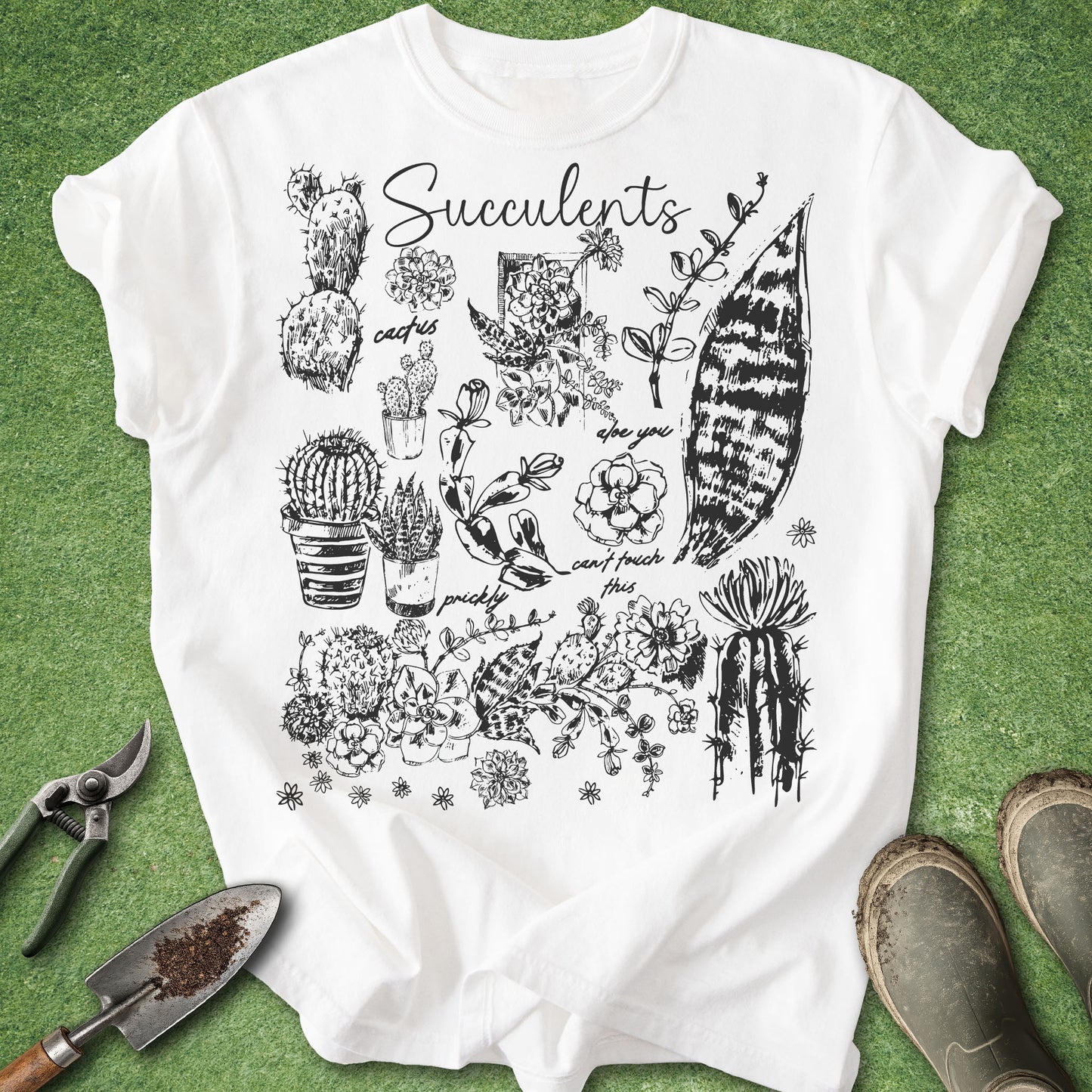 White t-shirt with black succulent illustrations on a green grass background