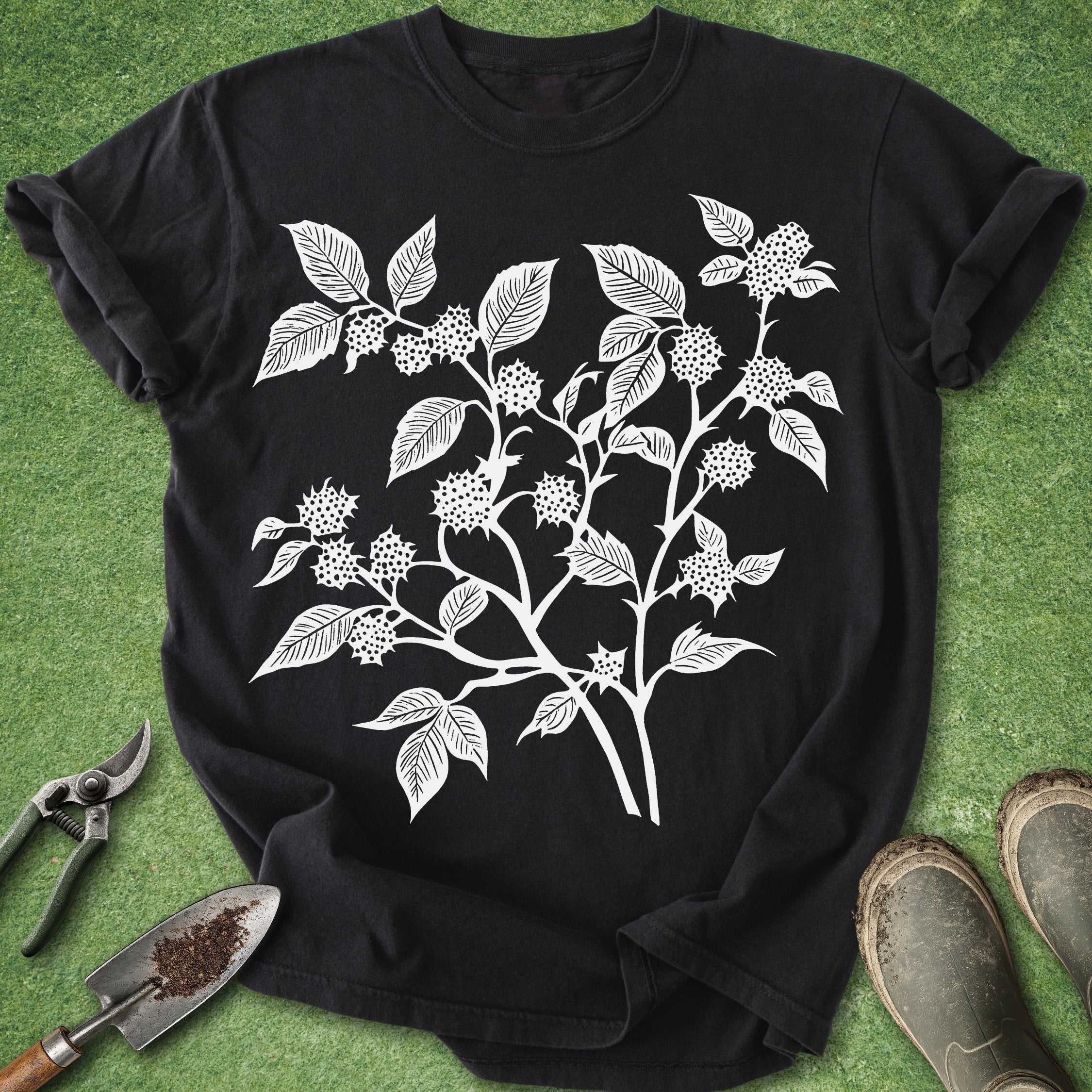 Black t-shirt with white floral design on a green grass background