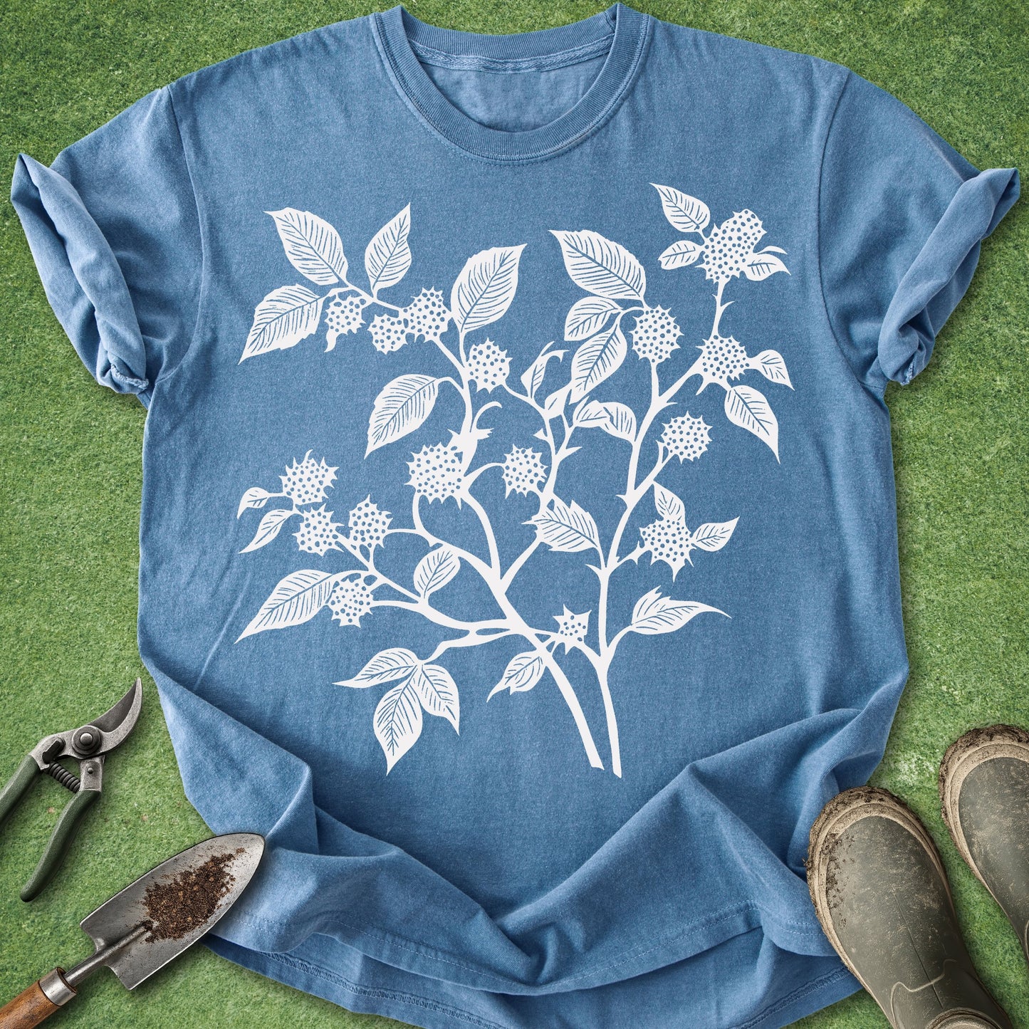 Blue t-shirt with white floral design on a green grass background
