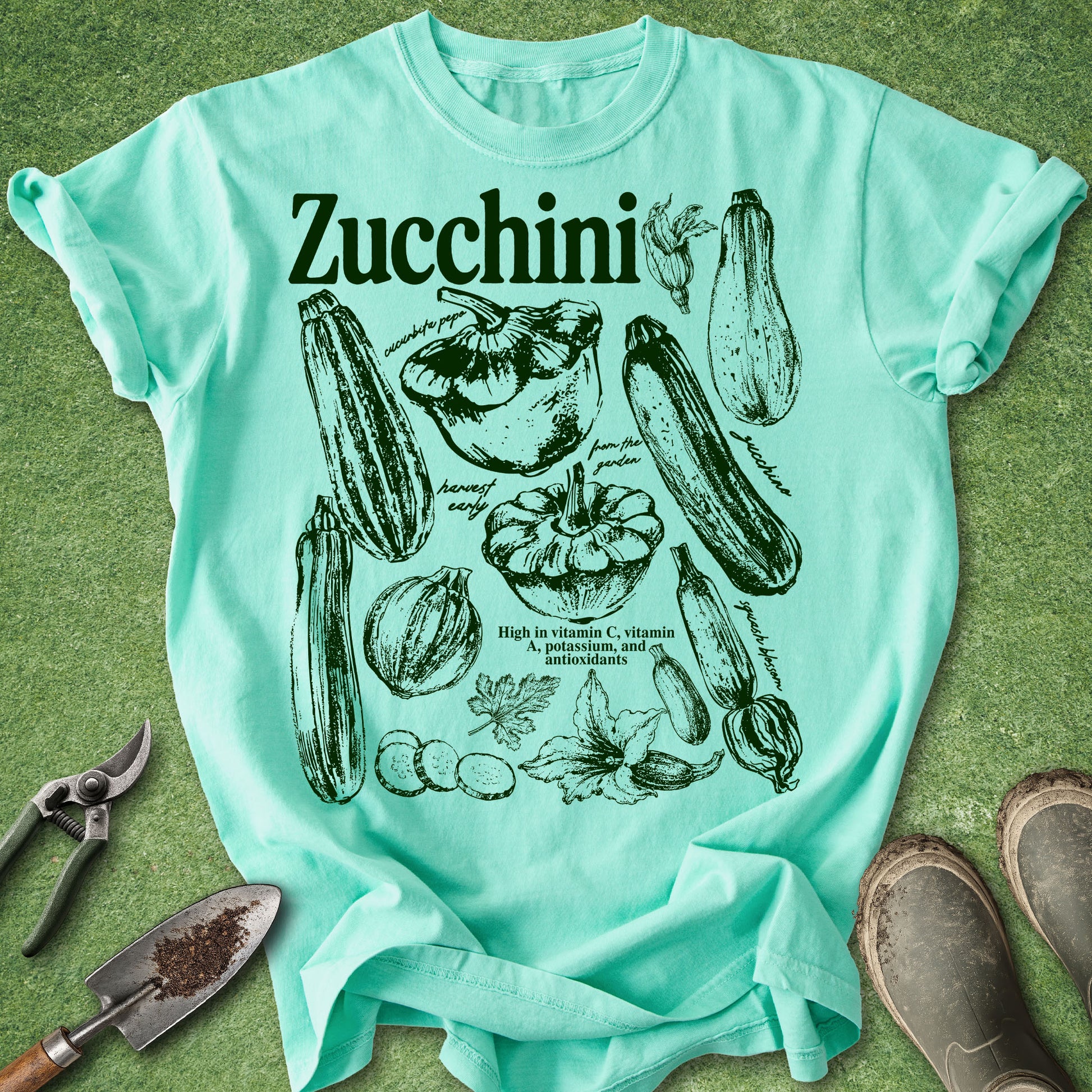 Mint green t-shirt with zucchini illustrations on a grass background