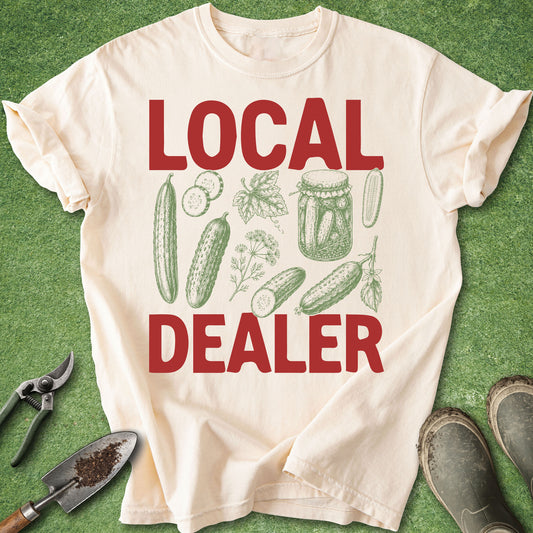 Ivory Comfort Colors t-shirt featuring the words "LOCAL DEALER" with vintage illustrations of cucumbers, dill, cucumber slices, and a mason jar filled with homemade pickles.