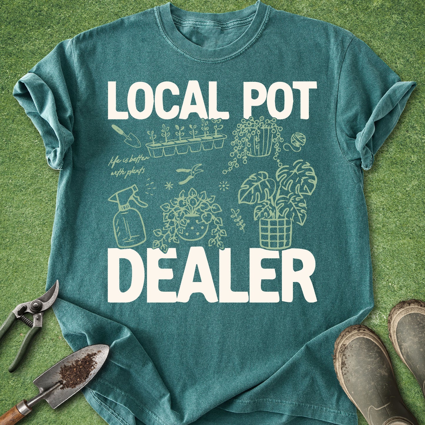 Blue Spruce Comfort Colors t-shirt featuring the phrase "Local Pot Dealer" with illustrated houseplants, propagation tray, watering spray bottle, pruning shears, hanging plant, monstera, and indoor gardening accessories.