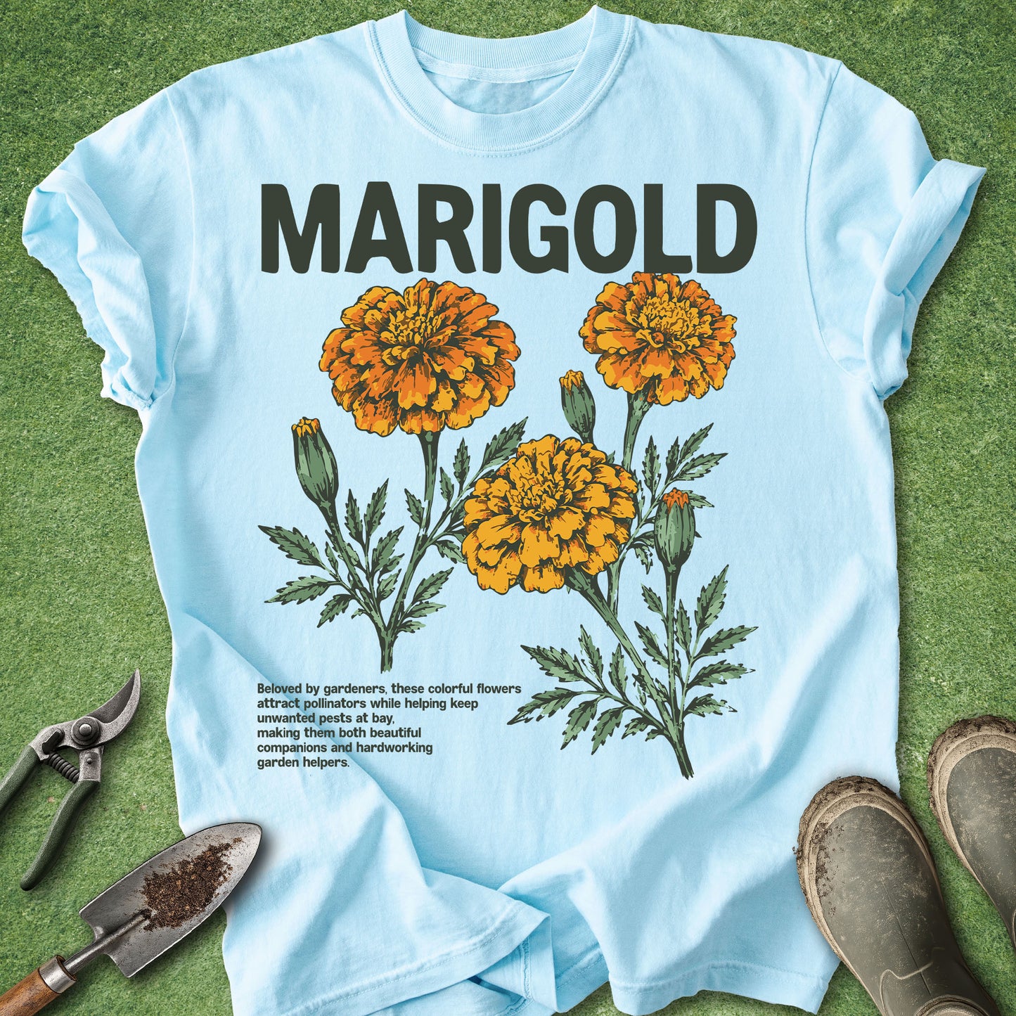 Chambray blue Comfort Colors t-shirt featuring bright orange marigold flowers in a vintage botanical illustration with the word "MARIGOLD" above the blooms.