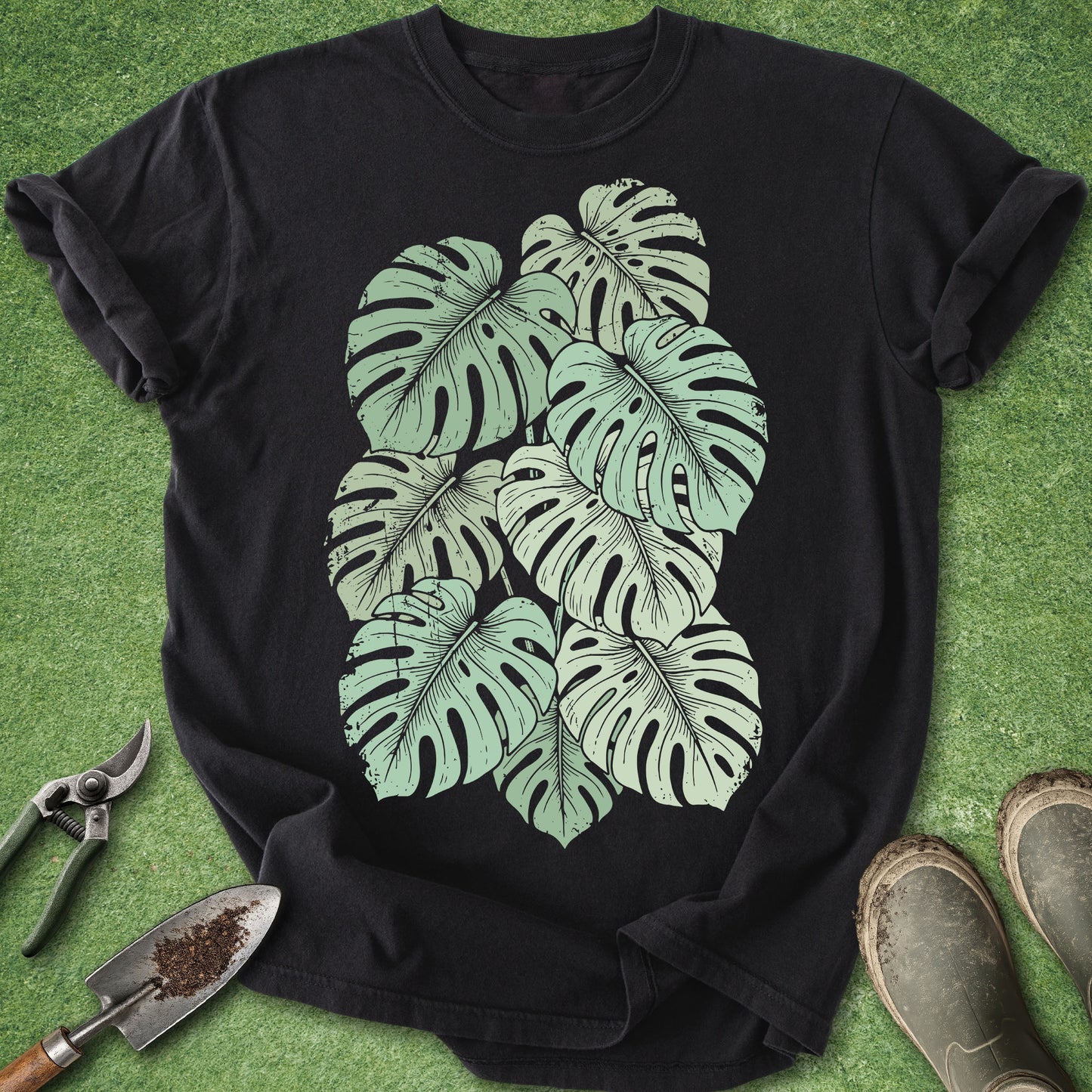 Black t-shirt with green leaf design on a grass background