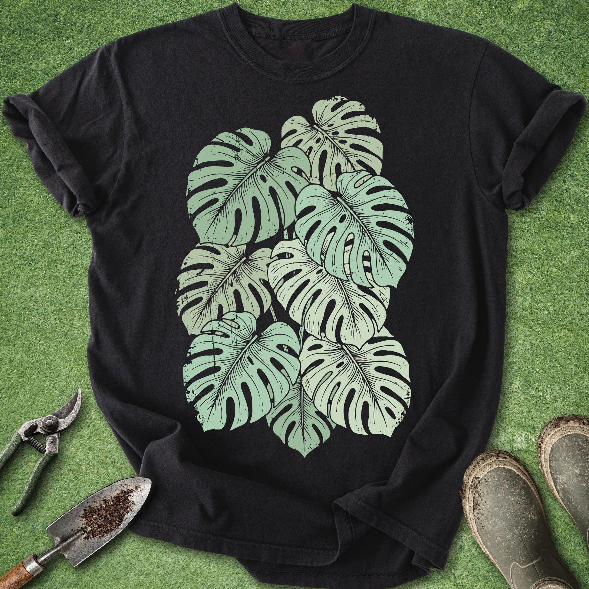 Black t-shirt with green leaf design on a grass background