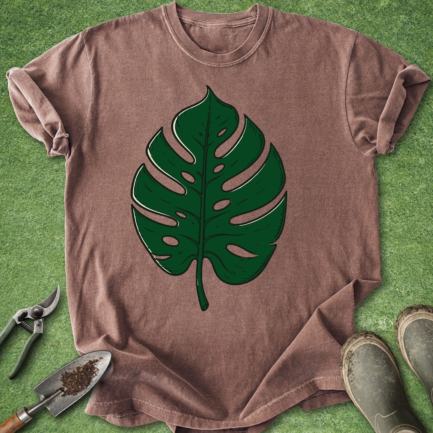 Brown t-shirt with green leaf design on a grass background