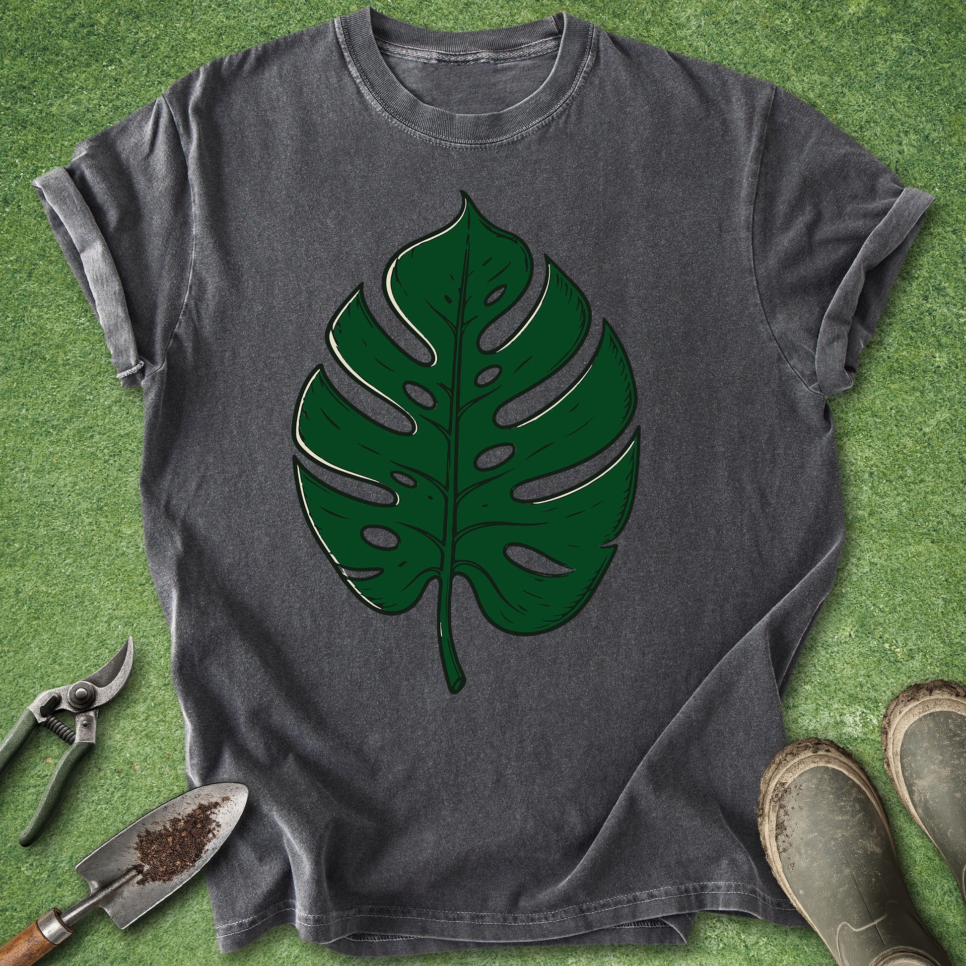 Gray t-shirt with green leaf design on a grass background