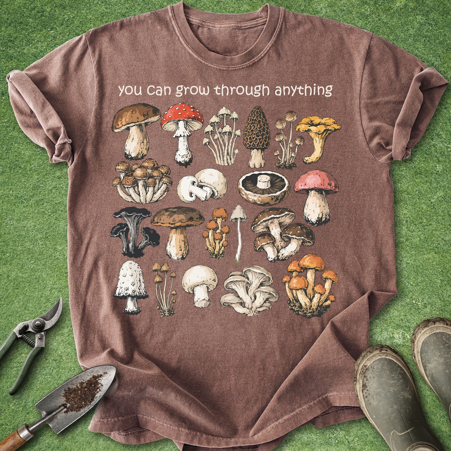 Brown t-shirt with mushroom illustrations and text on a green grass background