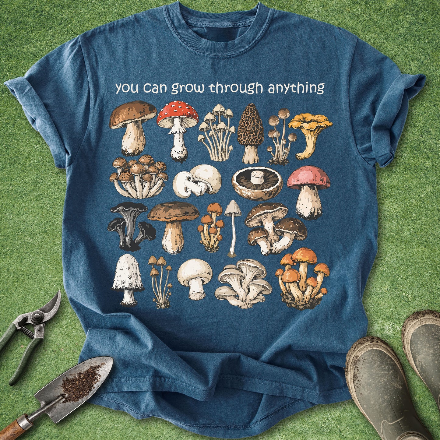 Blue t-shirt with mushroom illustrations and text on a grass background