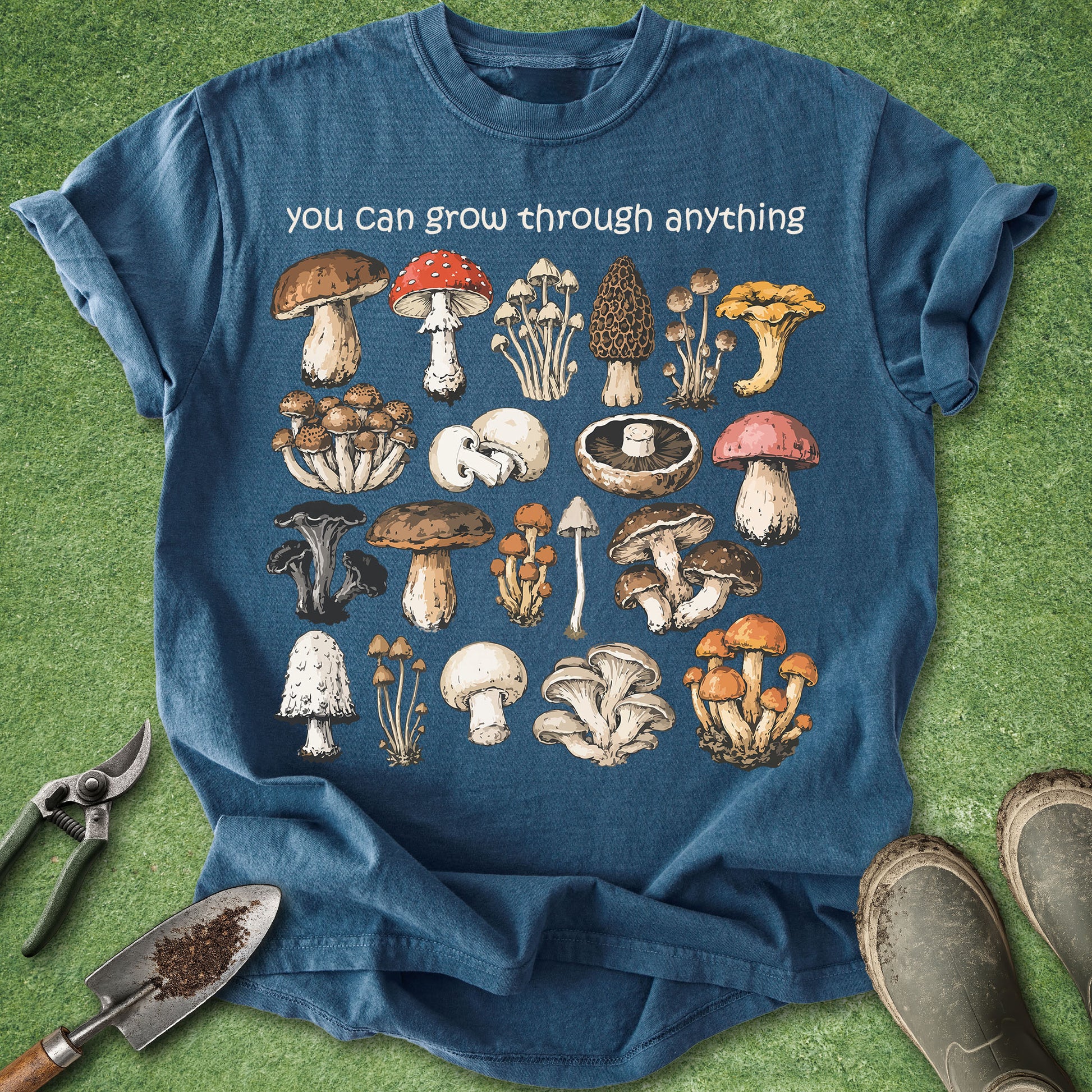 Blue t-shirt with mushroom illustrations and text on a grass background