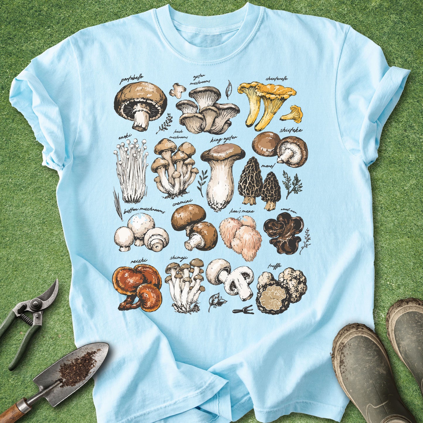 Light blue t-shirt with mushroom illustrations on a green grass background
