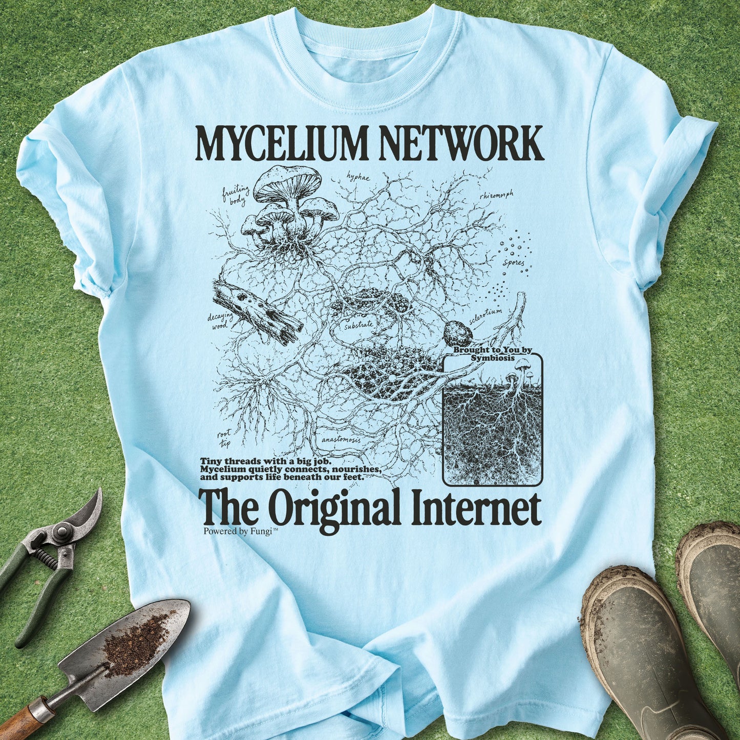Light blue t-shirt with black graphic design and text on a green grass background