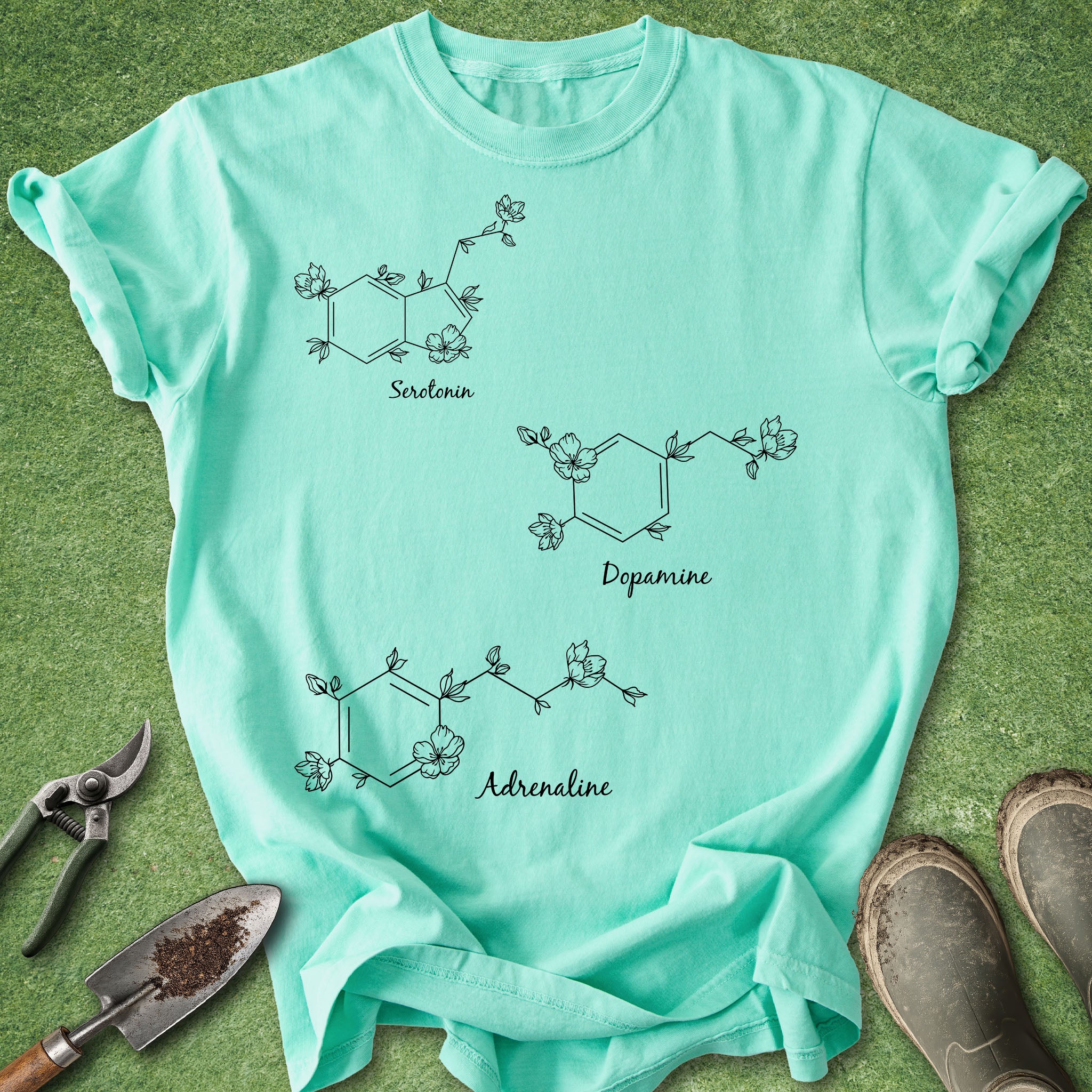 Mint green t-shirt with chemical formula designs on a grass background