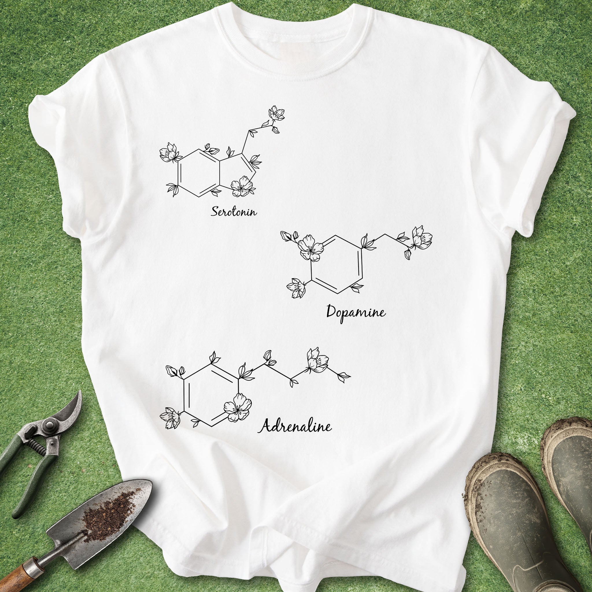 White t-shirt with chemical molecule designs and labels on a green grass background