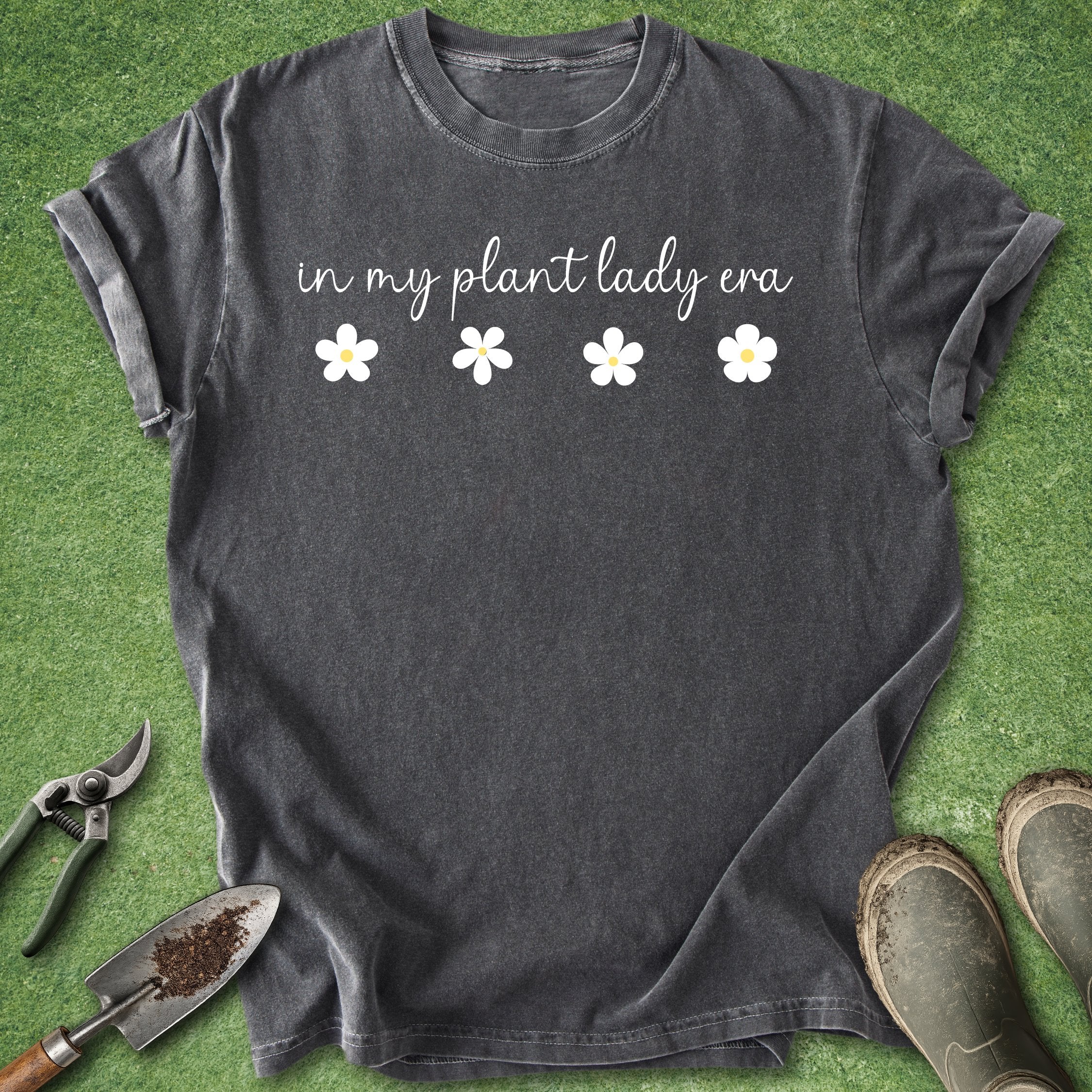 Black t-shirt with 'in my plant lady era' text and flowers on a grass background