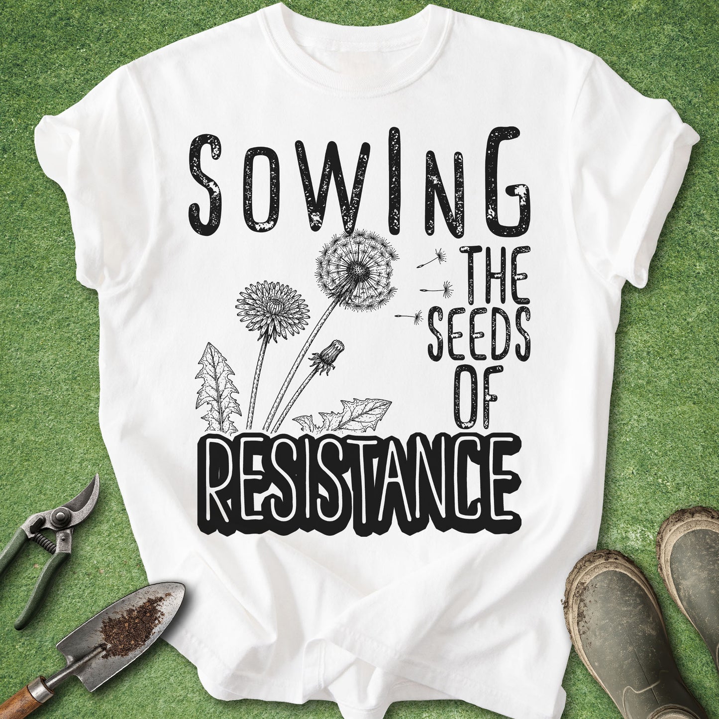White t-shirt with 'Sowing the Seeds of Resistance' text and dandelion graphics on a green background.