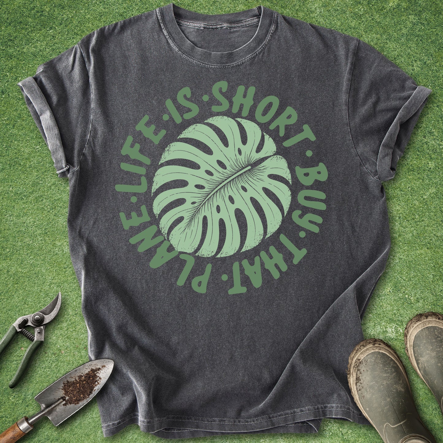 Gray t-shirt with green leaf graphic and text on a grass background