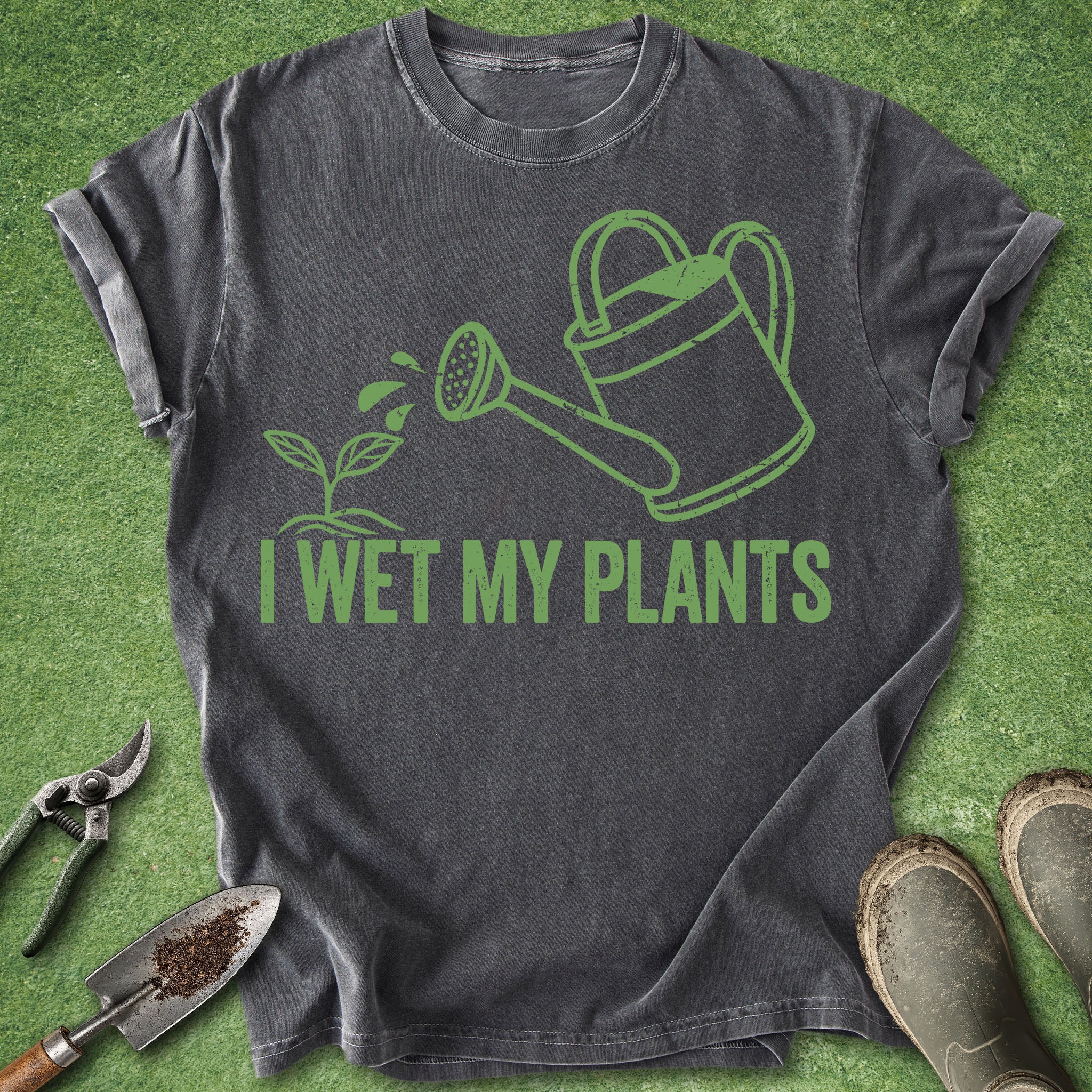 Gray t-shirt with green graphic and 'I Wet My Plants' text on a grass background