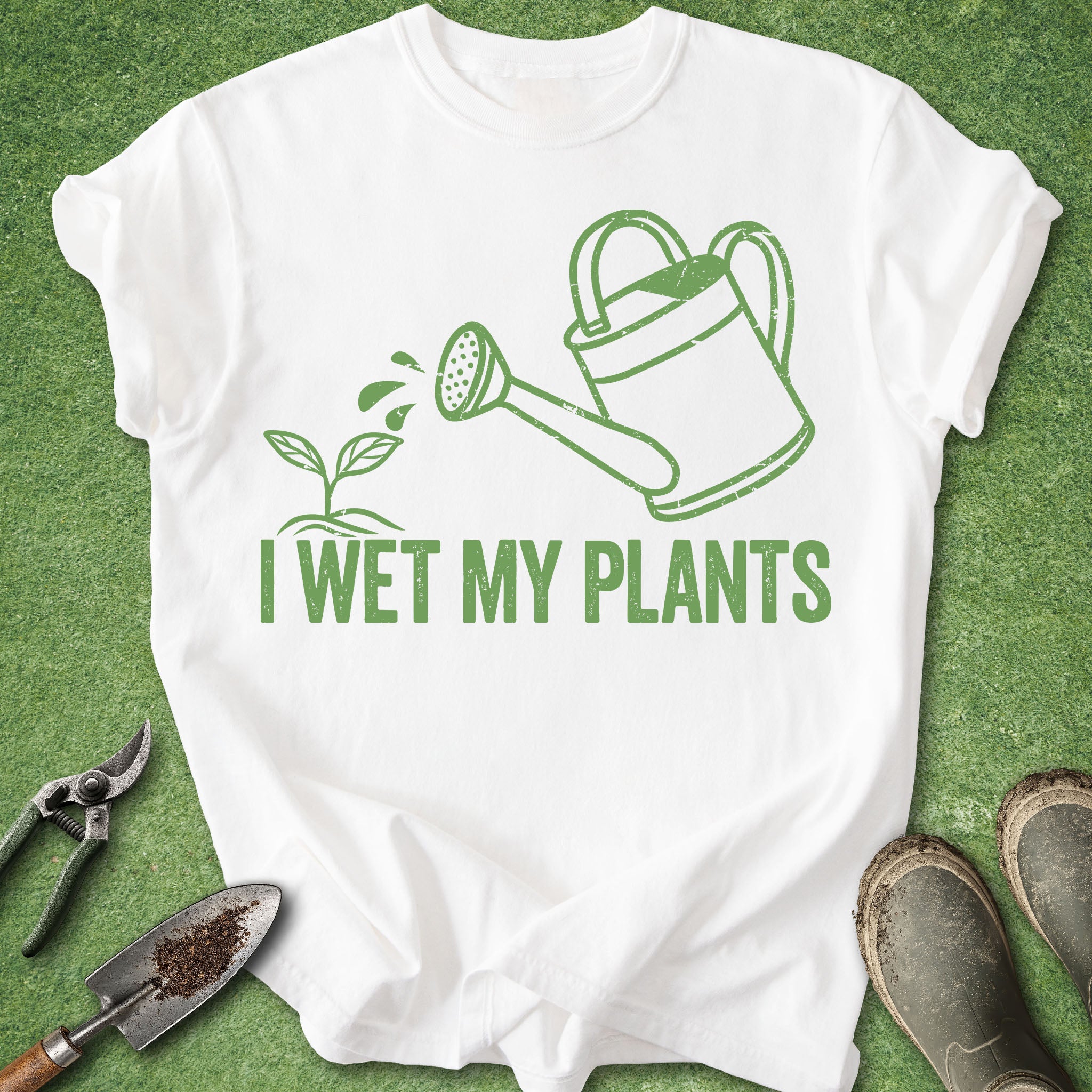 White t-shirt with gardening-themed design and tools on a green background