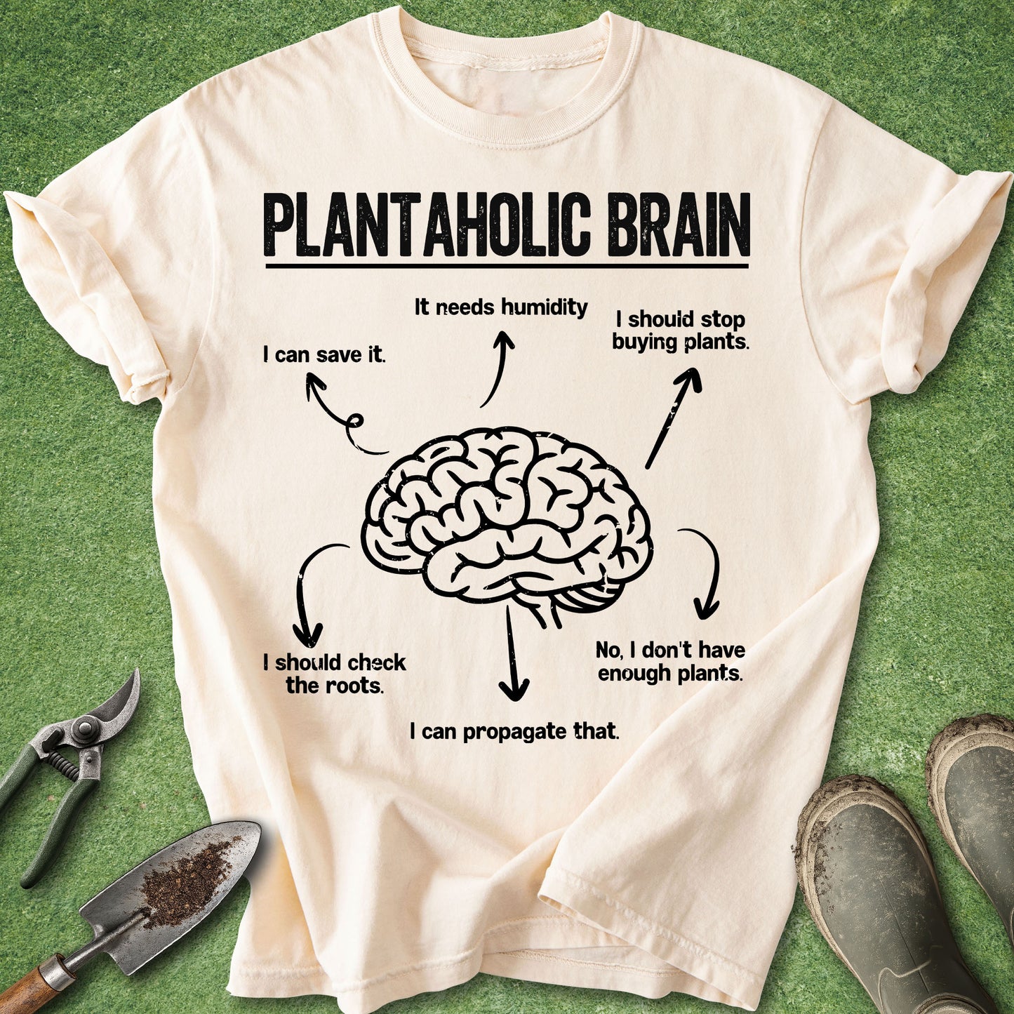 Beige t-shirt with brain graphic and text on a green background with gardening tools.