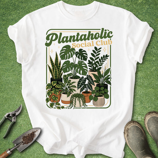 White t-shirt featuring “Plantaholic Social Club” text surrounded by a colorful retro illustration of potted monstera, snake plant, pothos, ZZ plant and other houseplants.