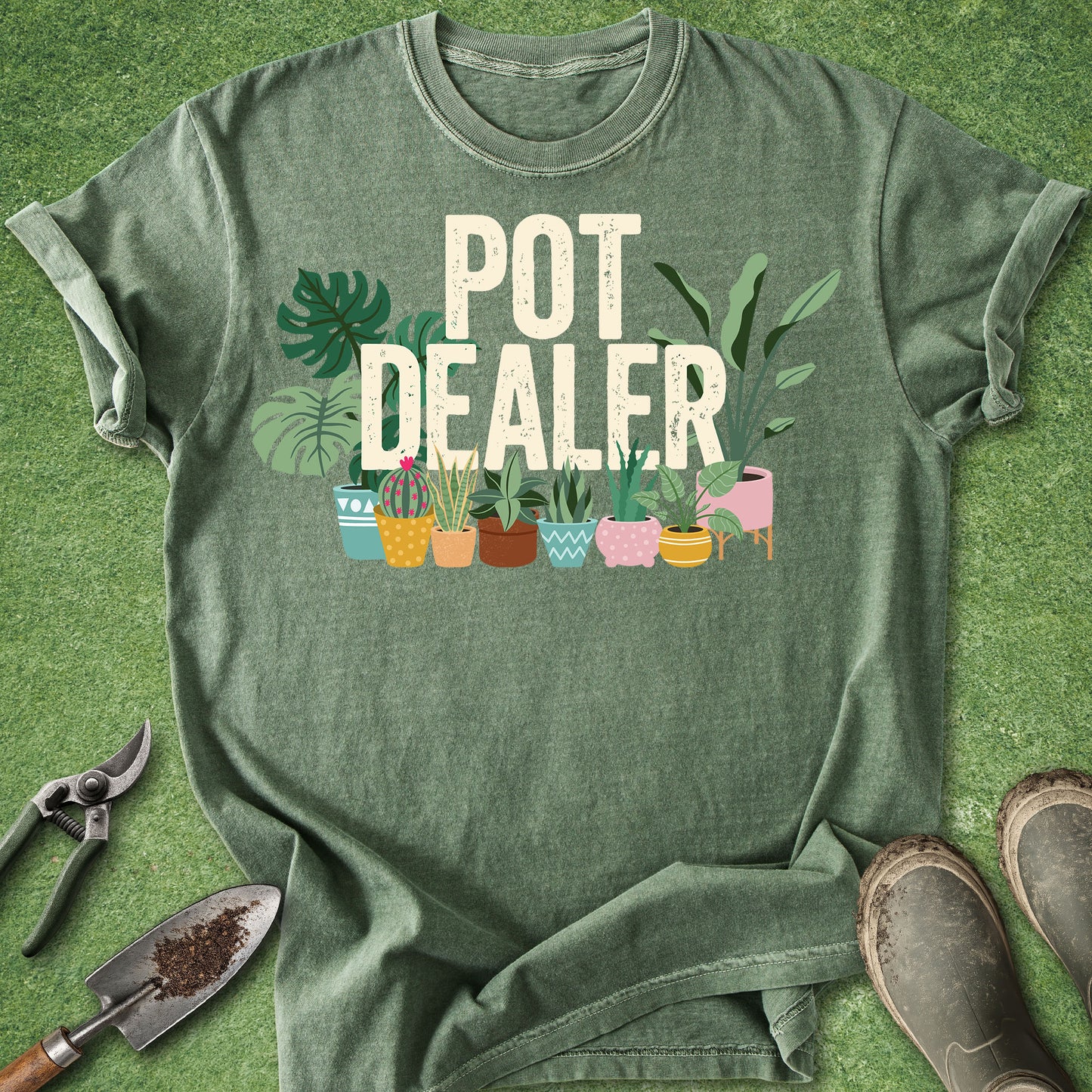 Moss Comfort Colors t-shirt featuring the phrase "Pot Dealer" above colorful illustrated potted houseplants including monstera, snake plants, cactus, and tropical foliage in decorative planters.