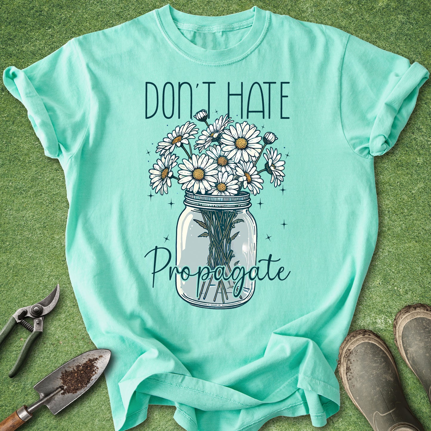 Mint green t-shirt with floral design and text on a grass background