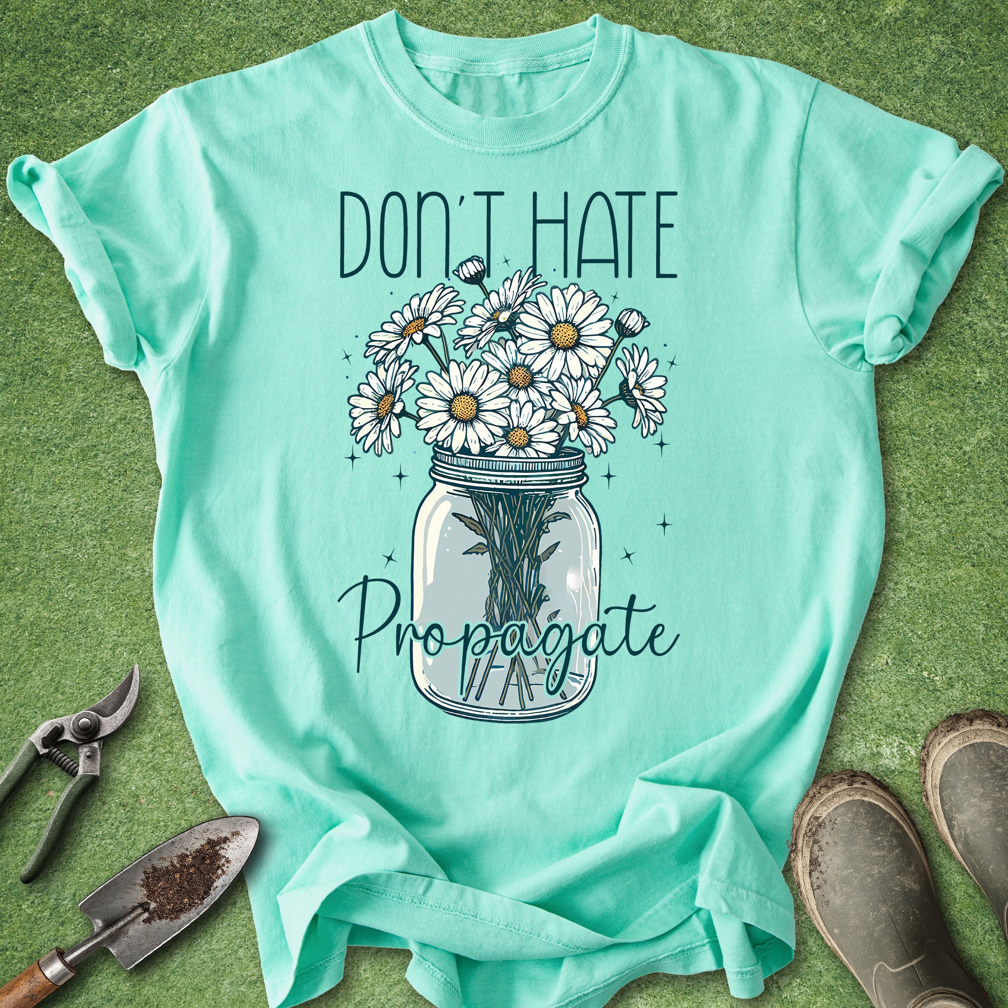 Mint green t-shirt with floral design and text on a grass background