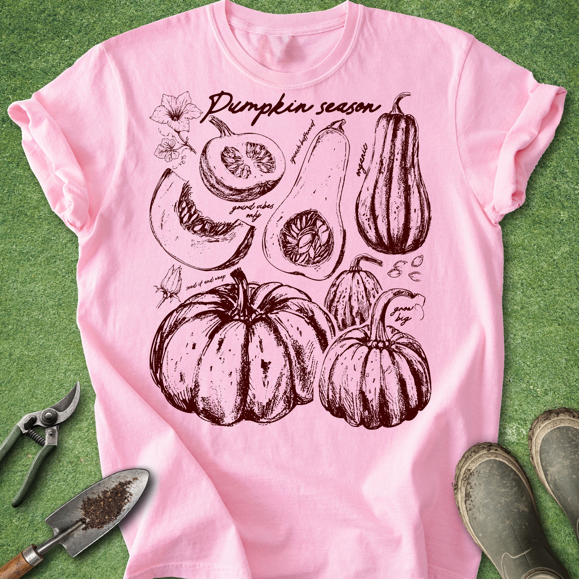 Pink t-shirt with pumpkin season design on a green background