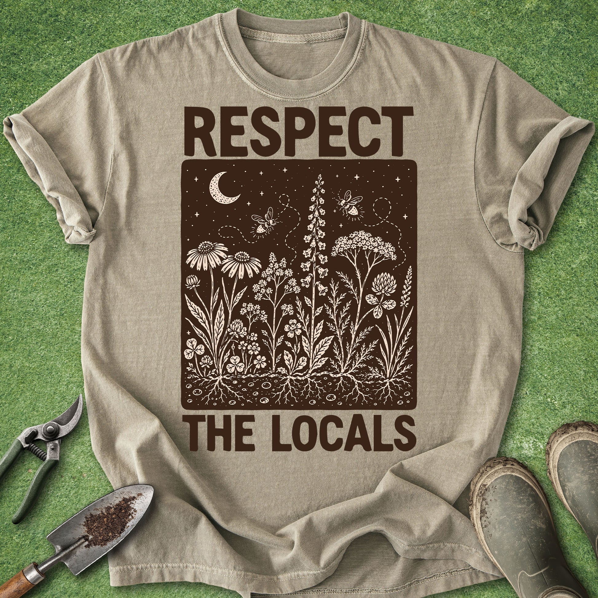 Khaki Comfort Colors t-shirt featuring the phrase "Respect The Locals" surrounding a detailed native wildflower meadow illustration with bees, moon, stars, and visible underground roots in a vintage folk-art style.