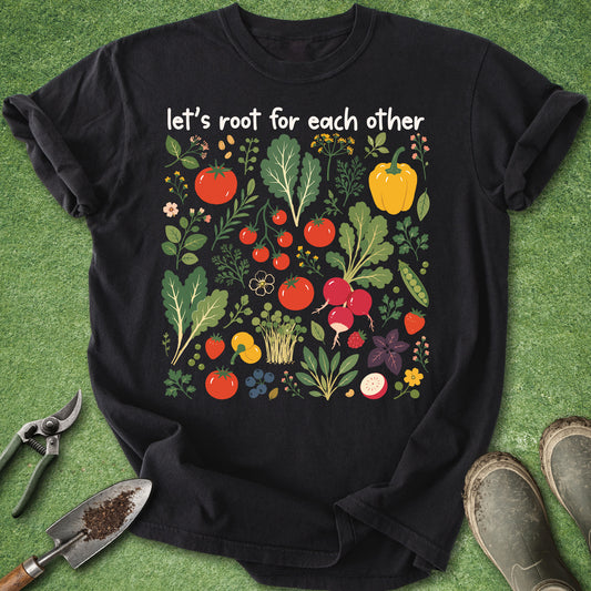 Black t-shirt with vegetable graphic and text 'let's root for each other' on a green background with gardening tools.