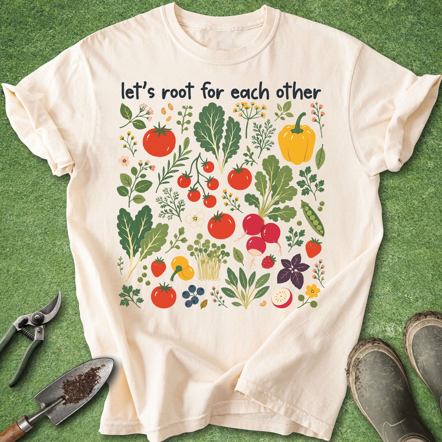 Ivory Comfort Colors t-shirt featuring colorful vegetables, herbs, flowers, and garden plants with the phrase "Let's Root for Each Other" above the artwork.